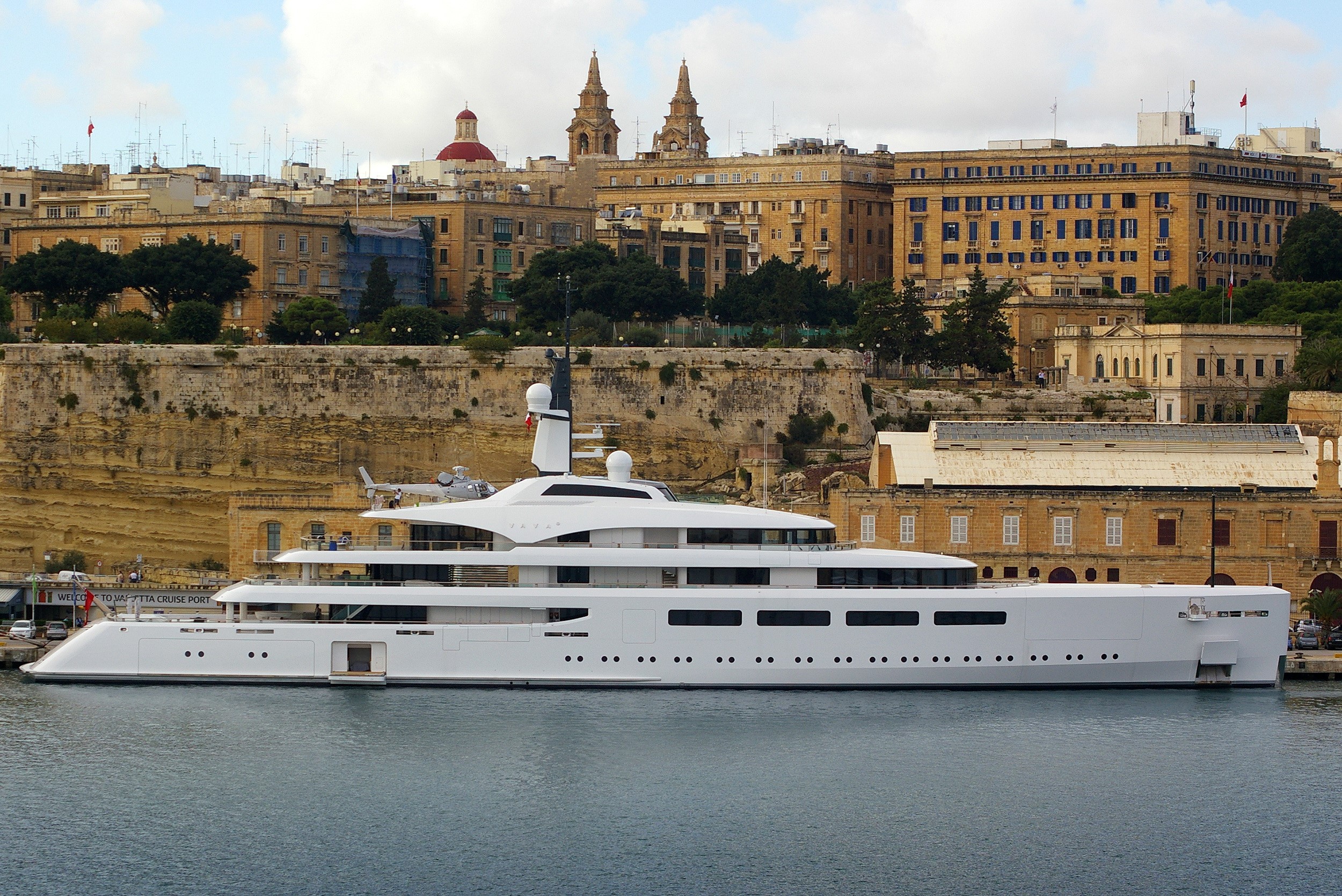 White luxury yacht docked in a harbor with city buildings HD Wallpaper