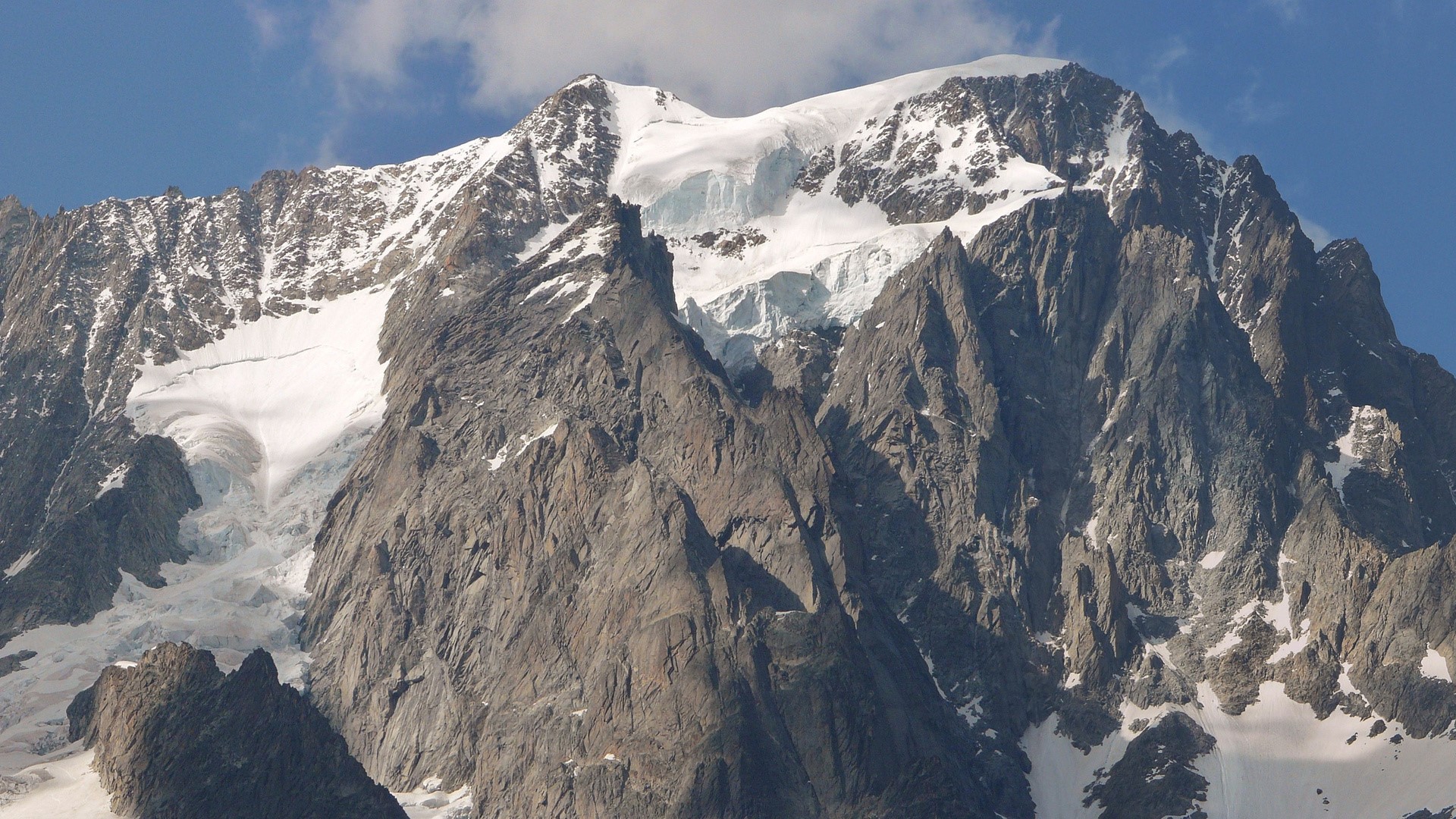 Snow-capped mountain range under a blue sky HD Wallpaper