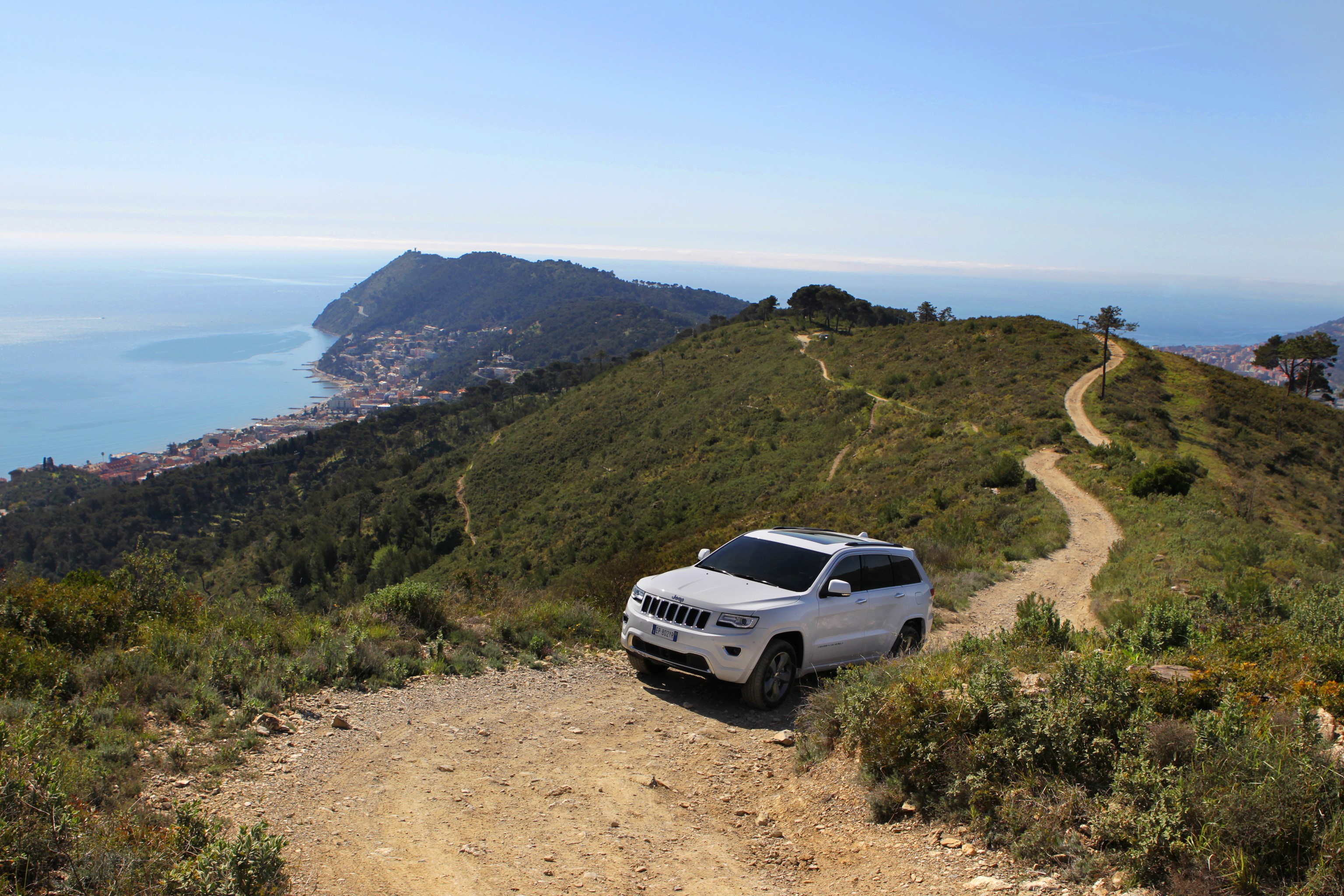 White Jeep Grand Cherokee on a mountain trail overlooking the sea HD Wallpaper
