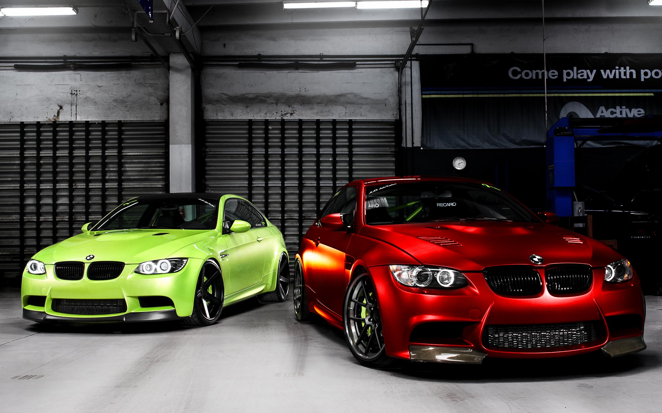 Two BMW M3s, one red and one lime green, in a garage HD Wallpaper