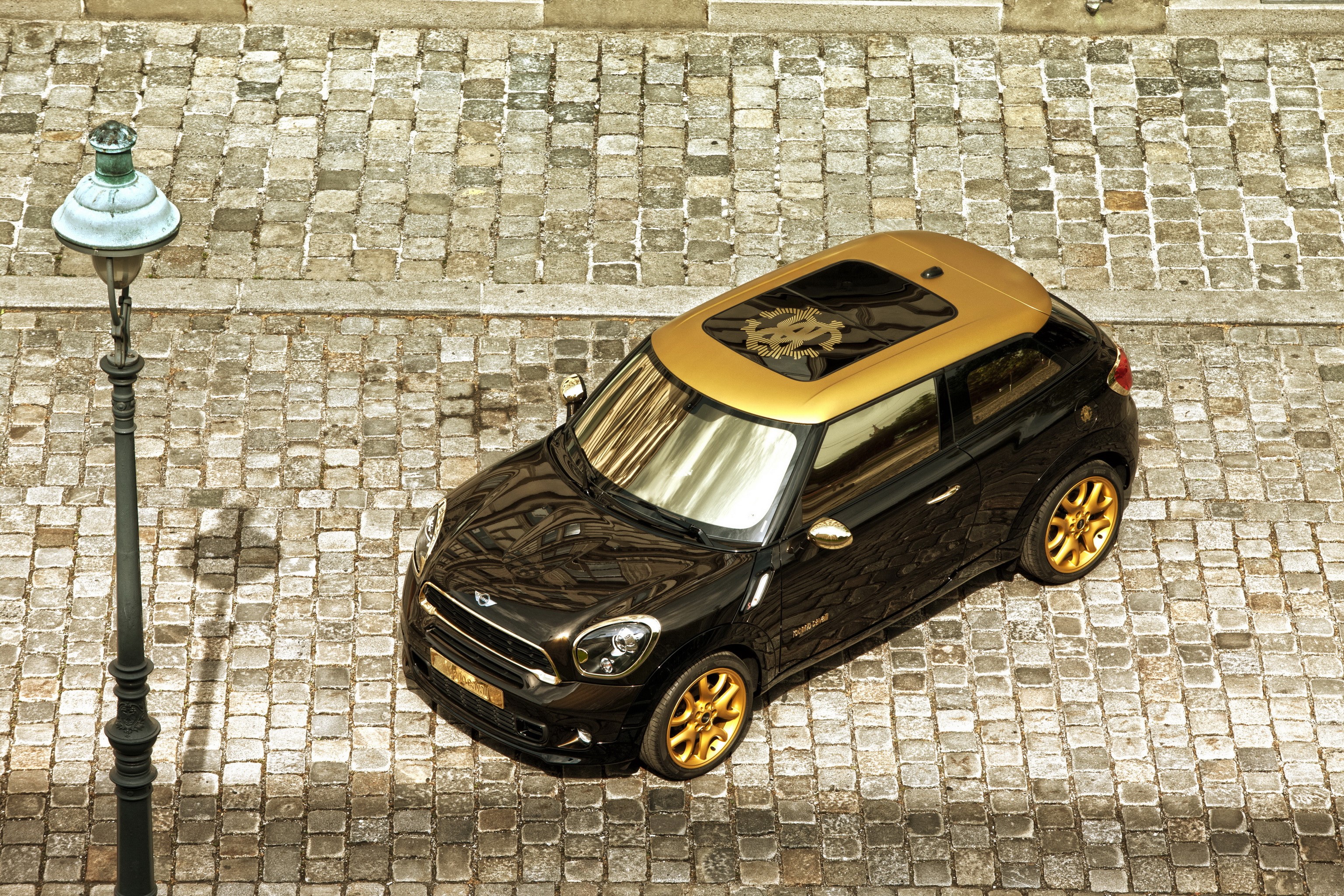 Black 2013 Mini Paceman Cooper S with gold accents on cobblestone street HD Wallpaper