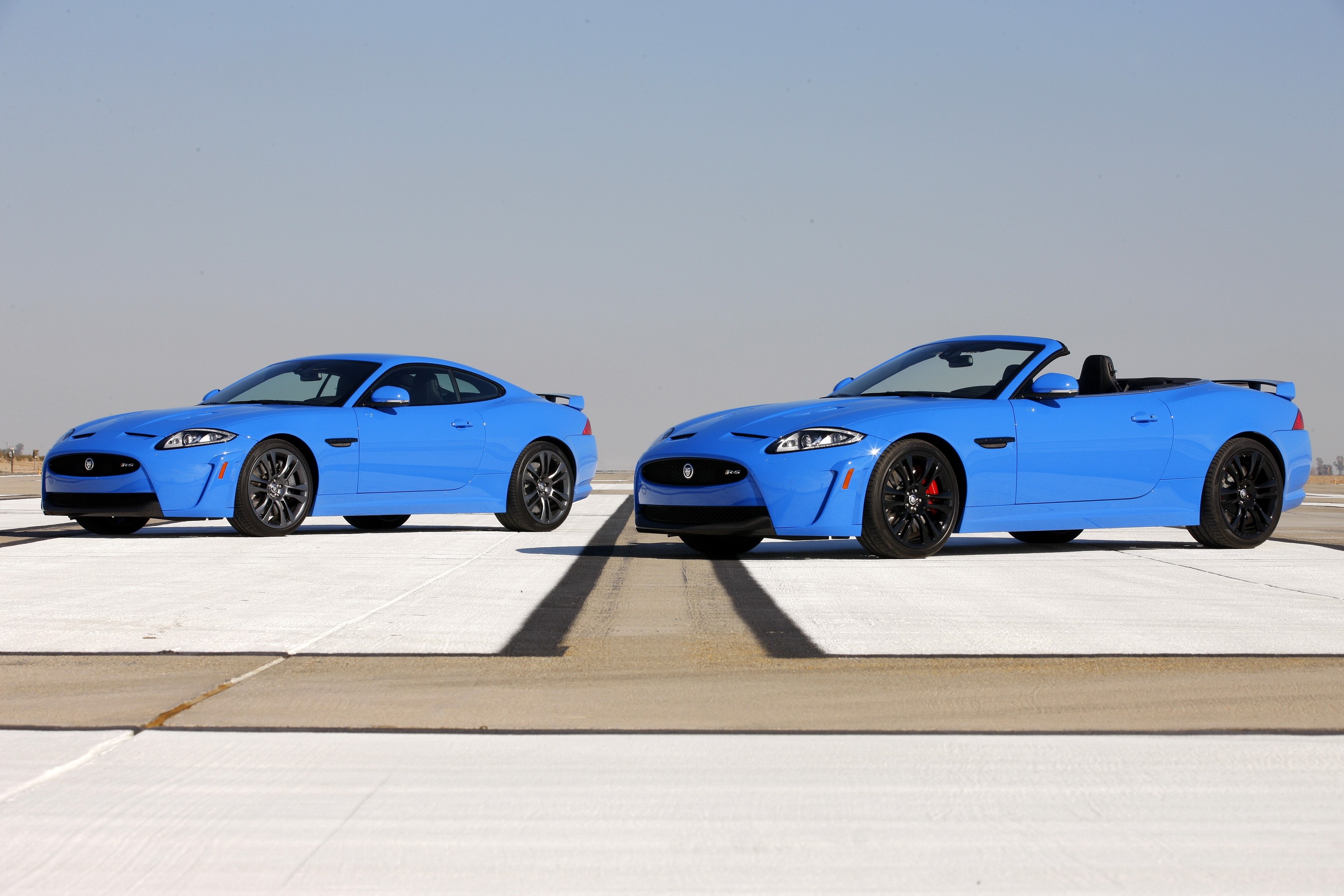 Two blue Jaguar XKRs on a runway HD Wallpaper