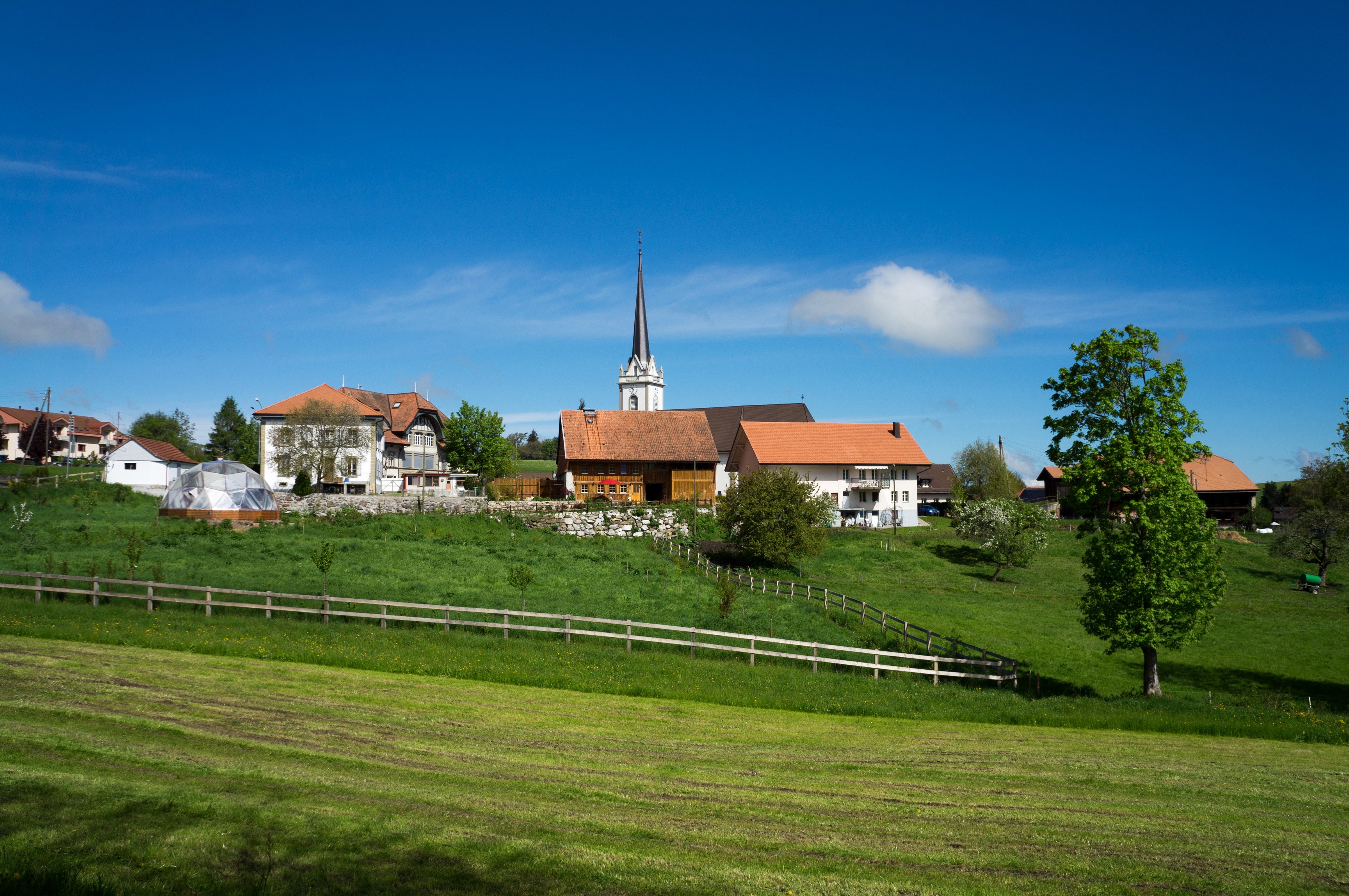 Village with church and green fields in Gruyere, Switzerland HD Wallpaper