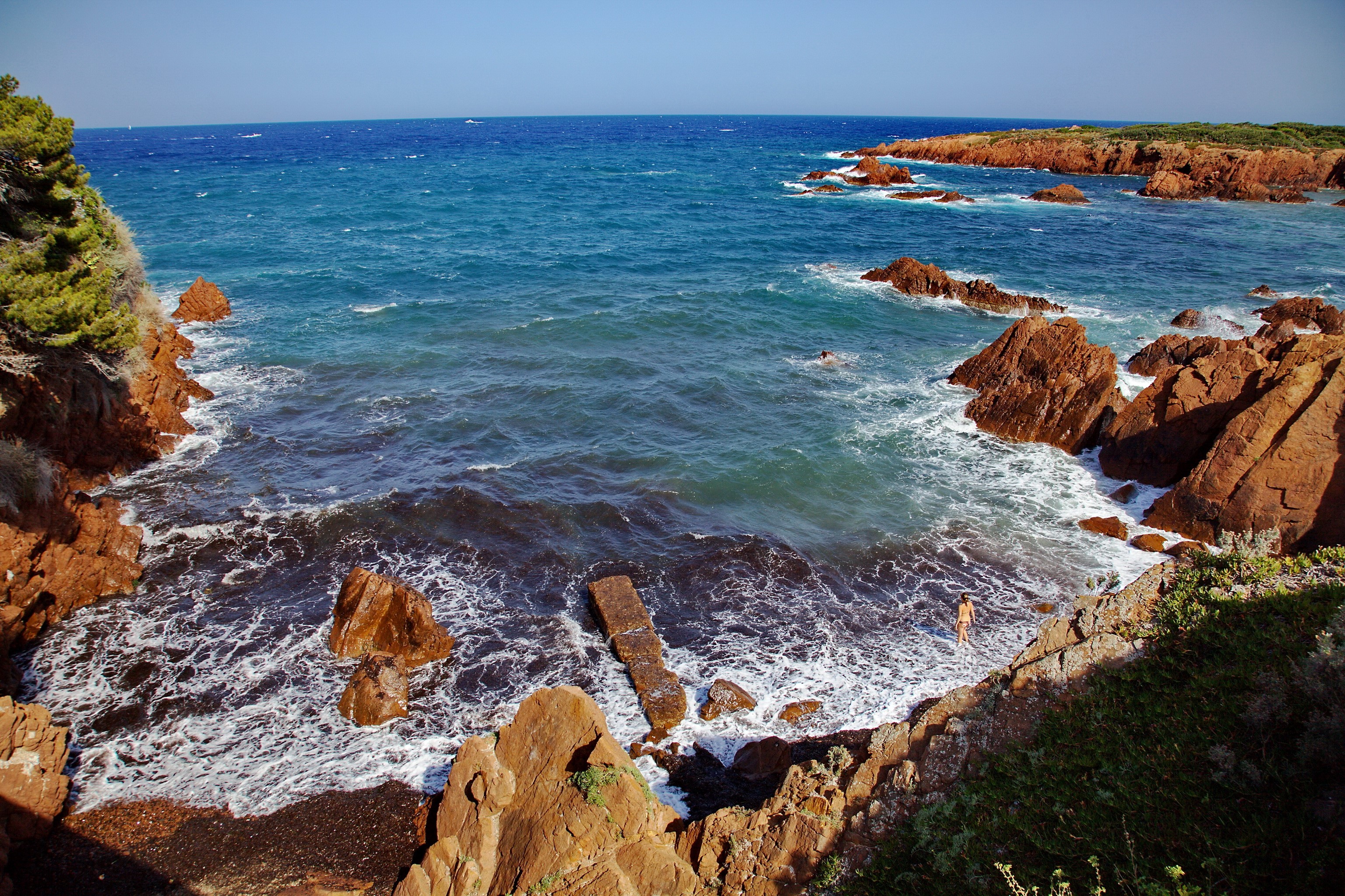 Rocky Coastline with Turquoise Water and Two Swimmers HD Wallpaper
