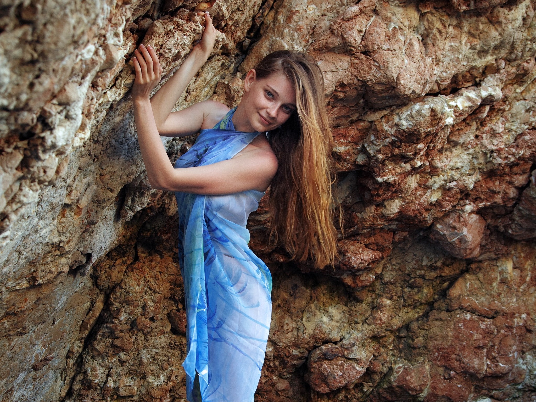 Ann Glazyrina in a blue sarong against rocks HD Wallpaper