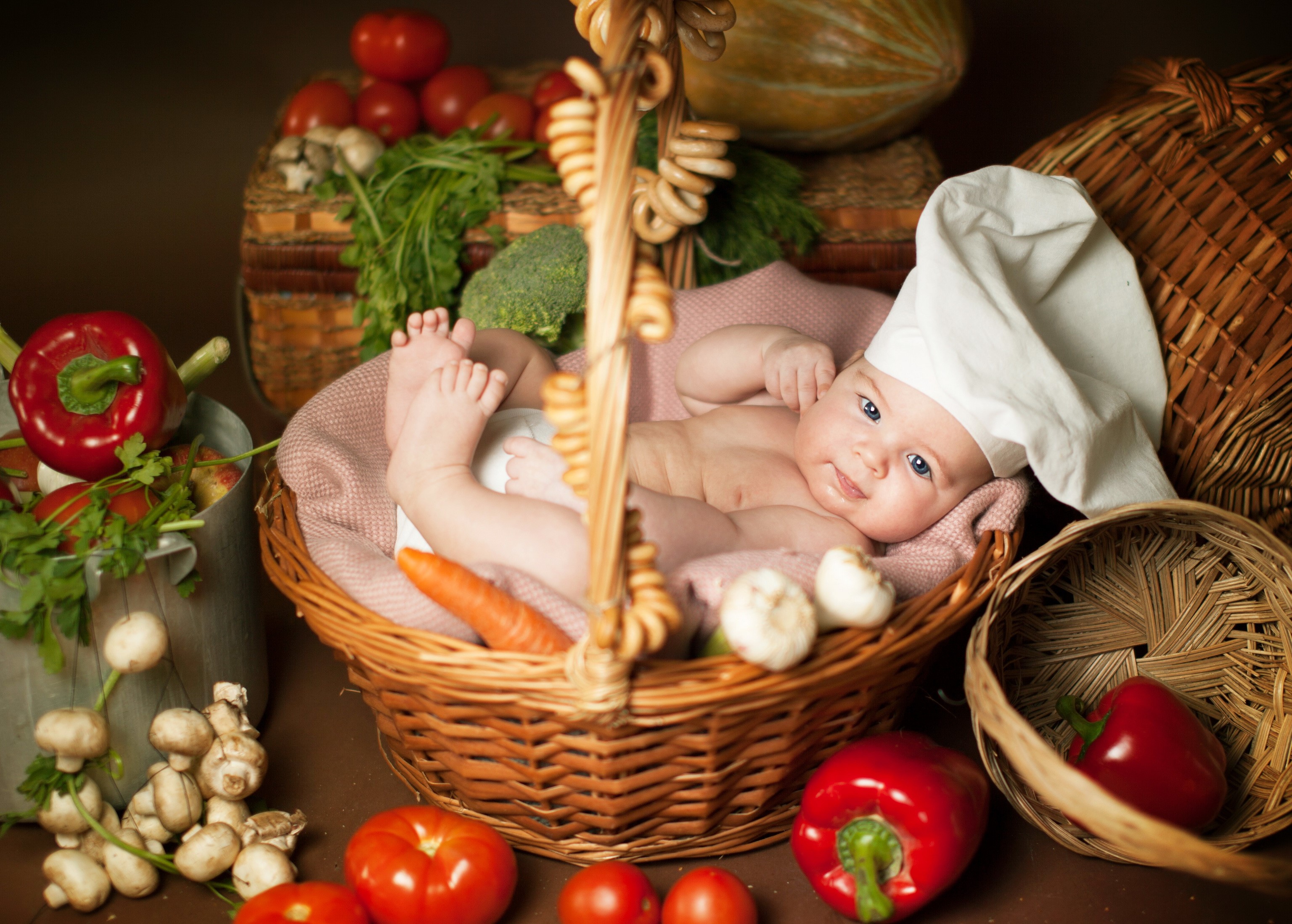 Baby in chef hat in a basket with vegetables HD Wallpaper