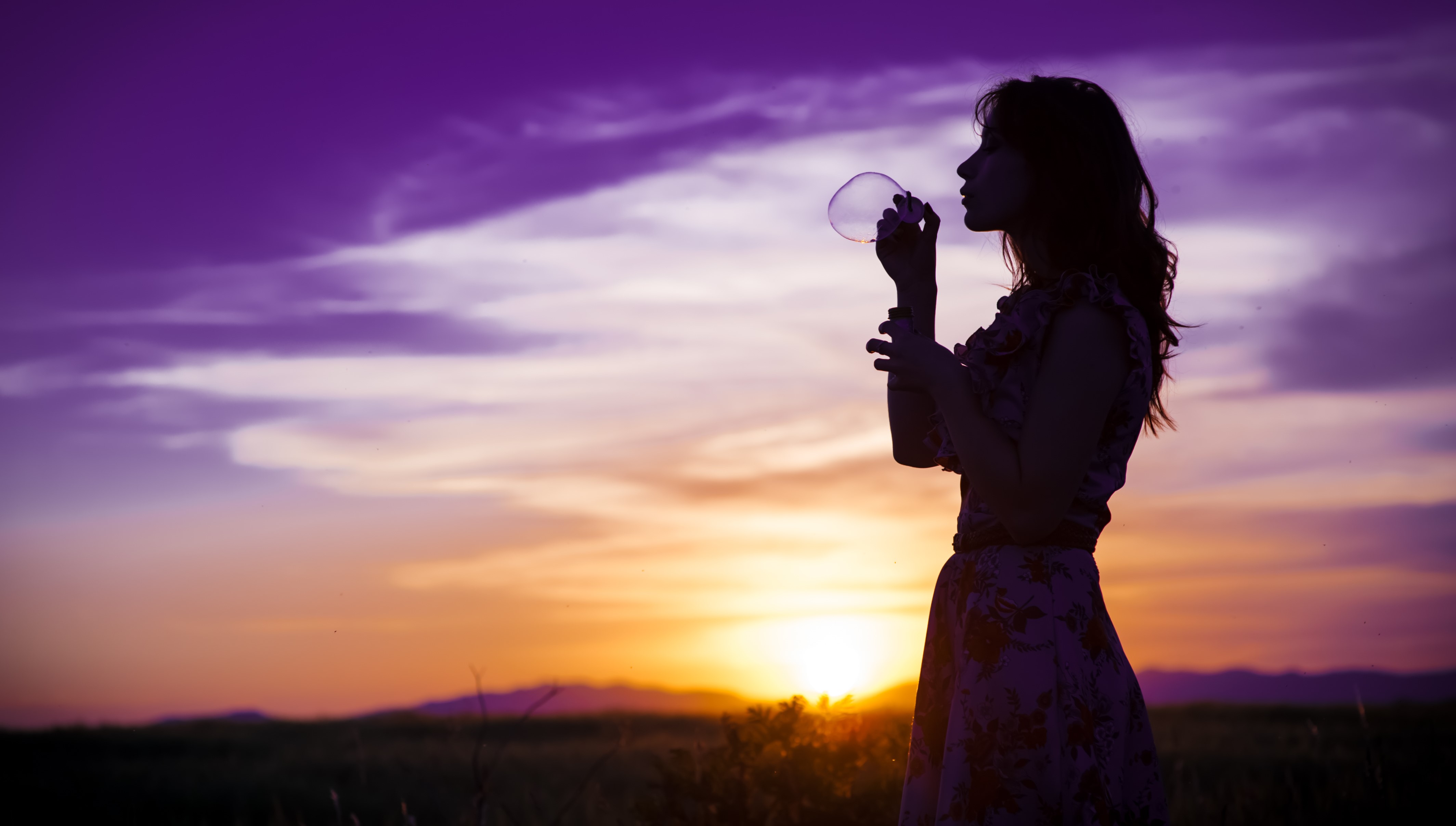 Silhouette of a woman blowing bubbles at sunset HD Wallpaper