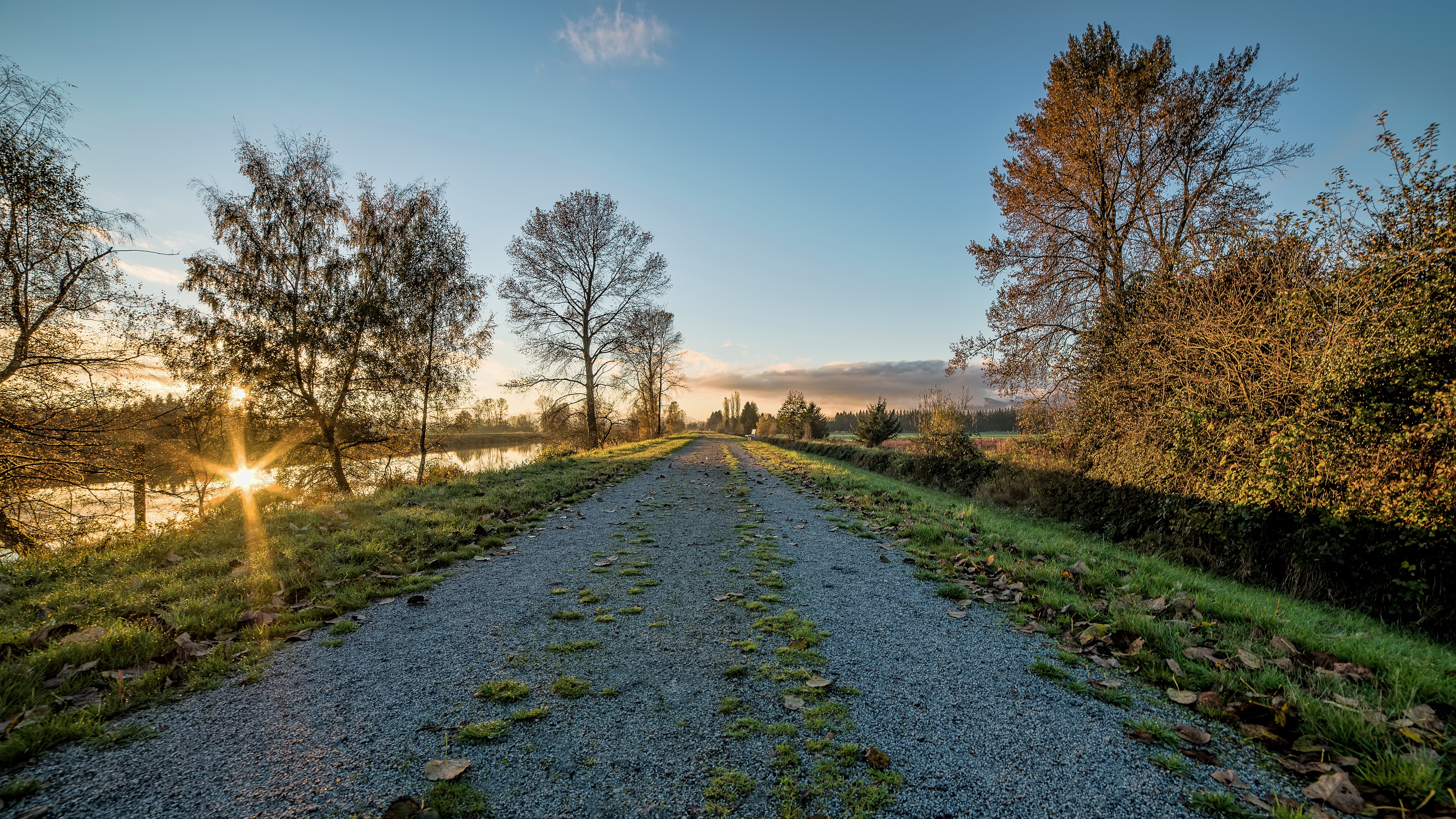 Gravel path along a lake at sunrise HD Wallpaper