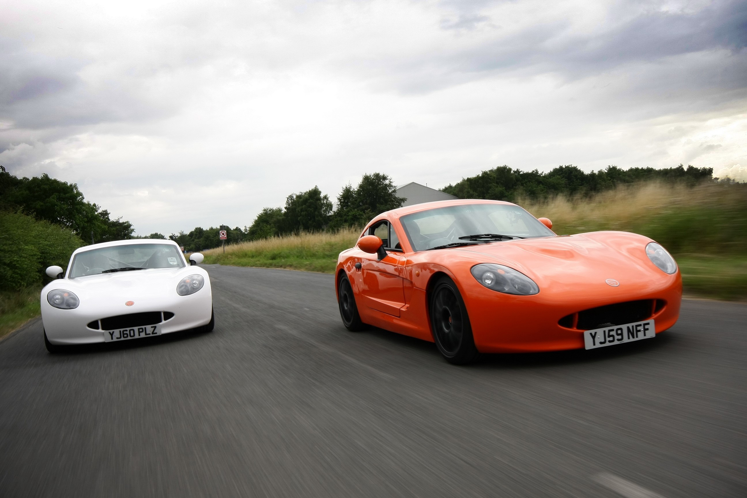 Two Ginetta G40R sports cars on a road HD Wallpaper