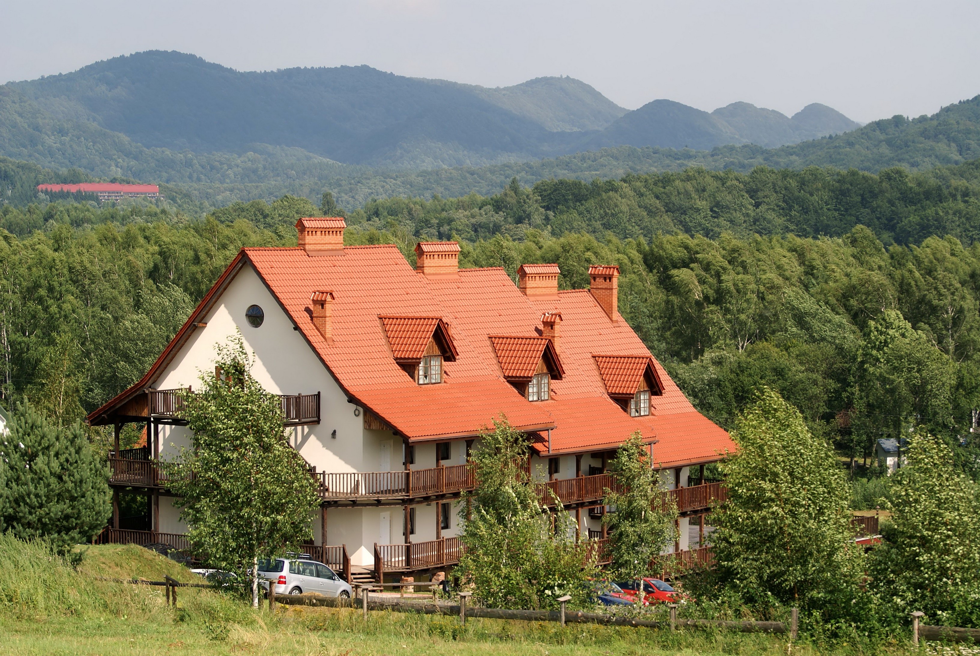Large house with red roof in a forest with mountains HD Wallpaper