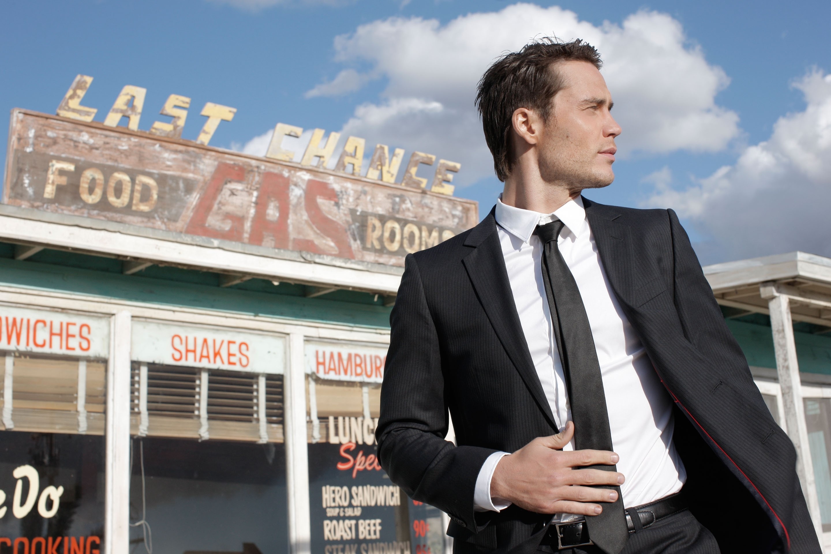Man in suit in front of a vintage gas station HD Wallpaper