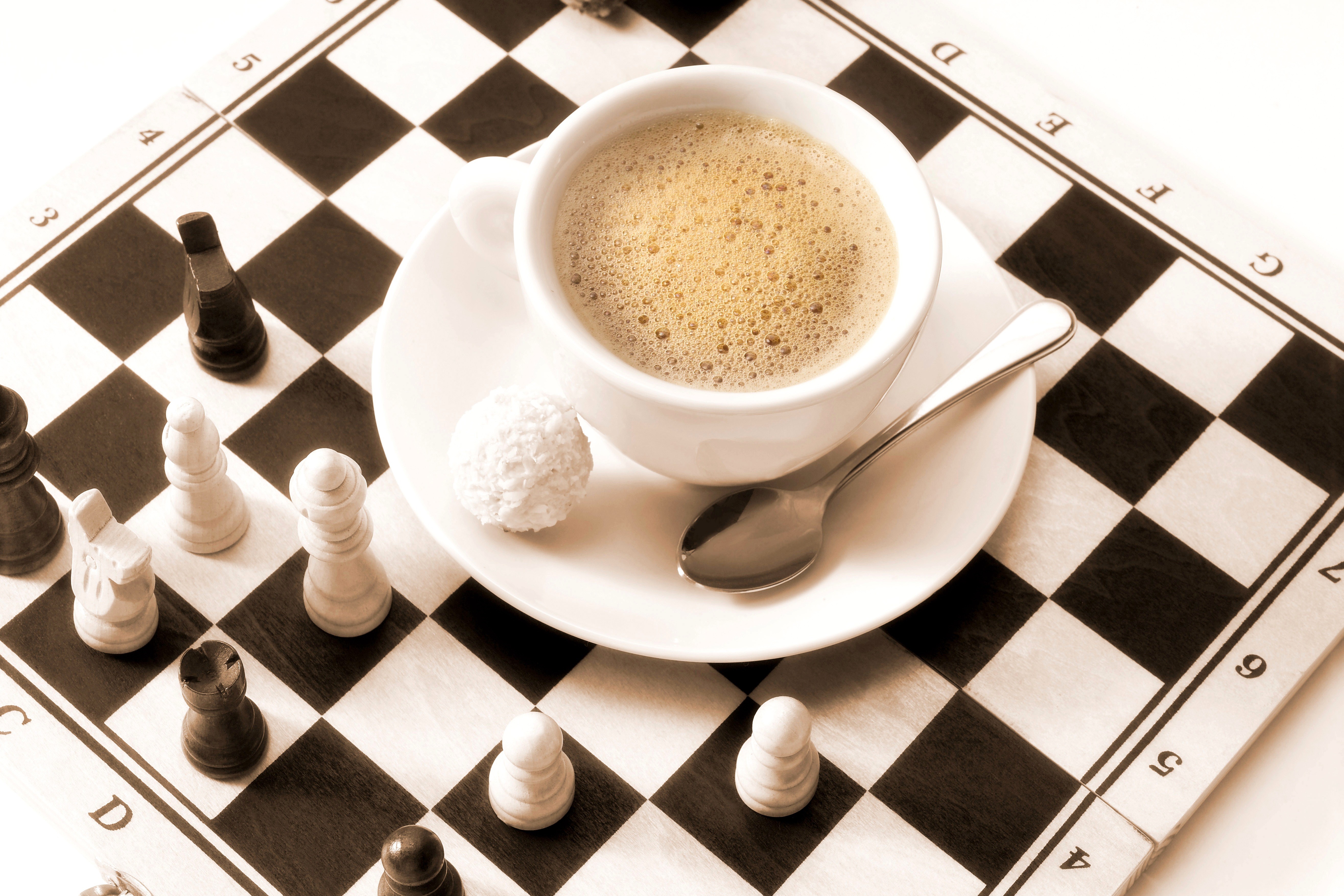 Coffee cup and saucer on a chessboard with chess pieces HD Wallpaper