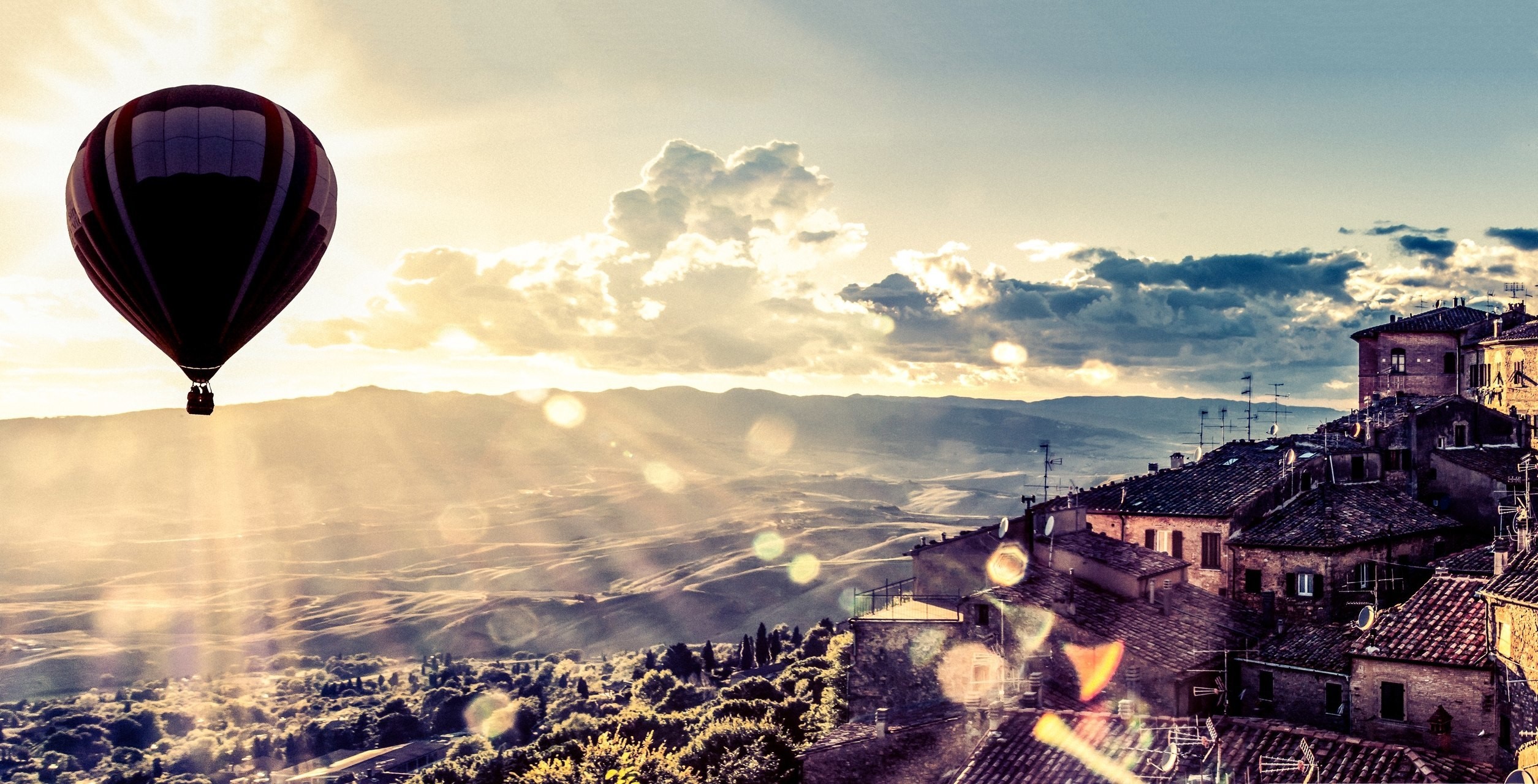 Hot air balloon over Tuscan village at sunset HD Wallpaper
