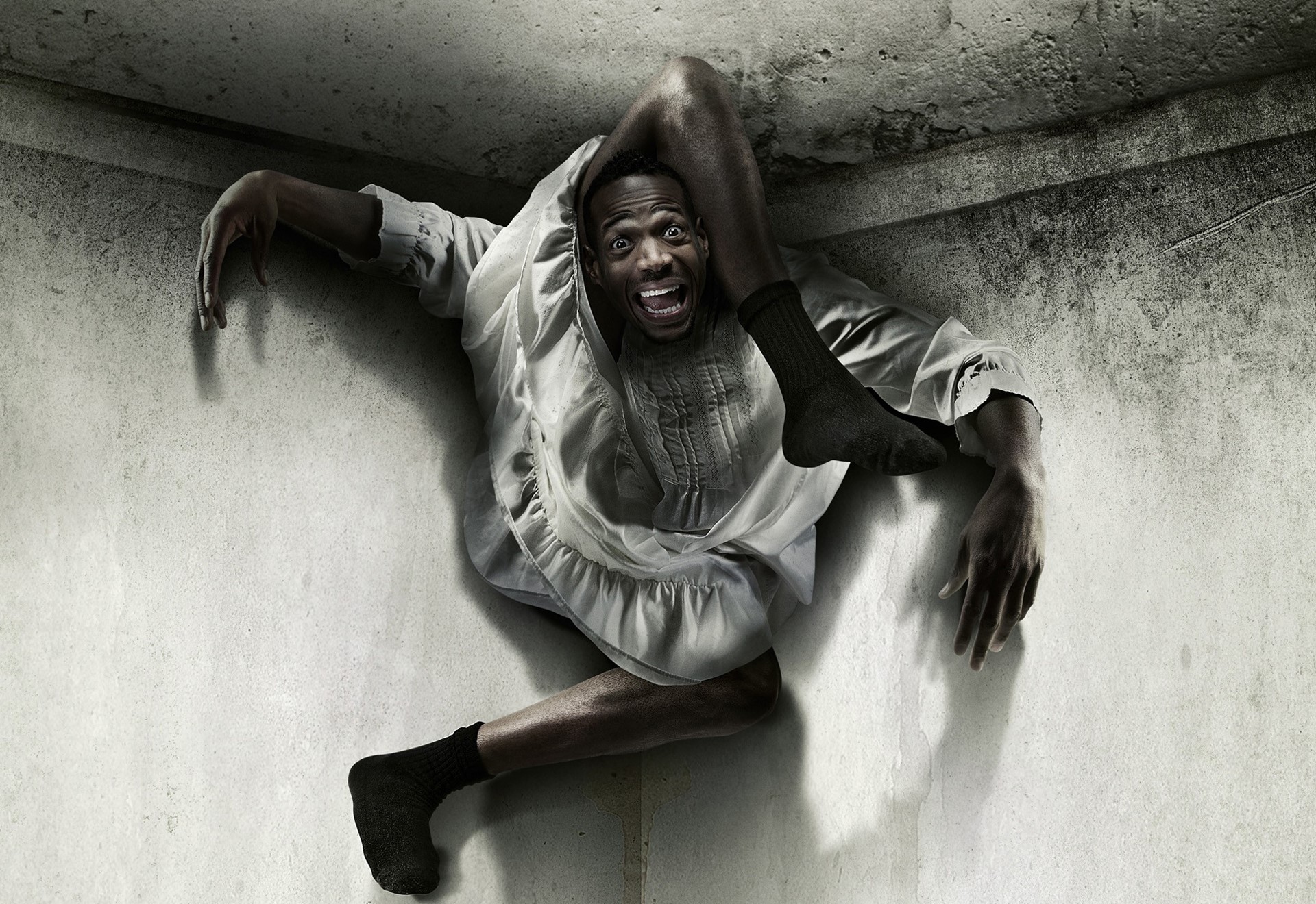Man contorted in a corner, wearing a dress and socks HD Wallpaper