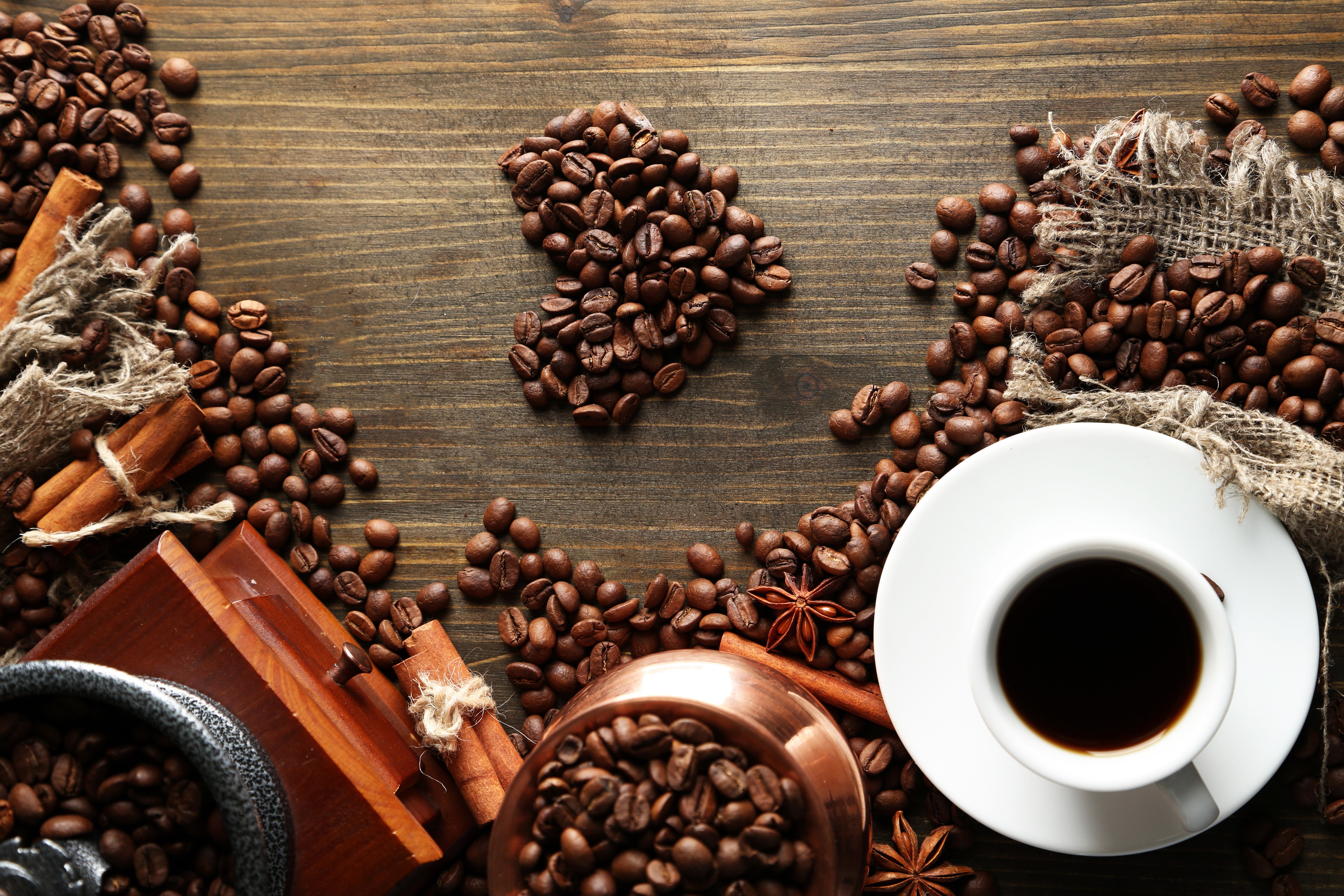 Coffee beans arranged in a heart shape with cinnamon sticks and a cup of coffee HD Wallpaper