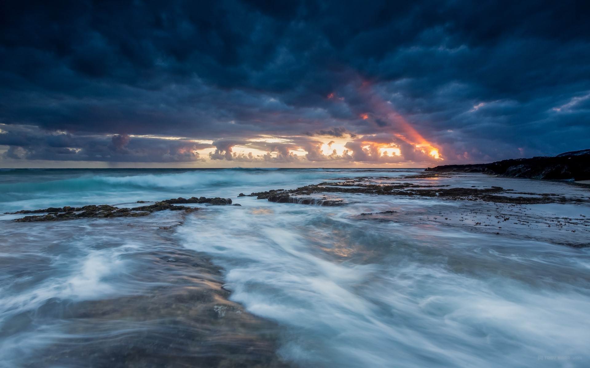Ocean waves crashing on rocky shore at sunset with dramatic clouds HD Wallpaper