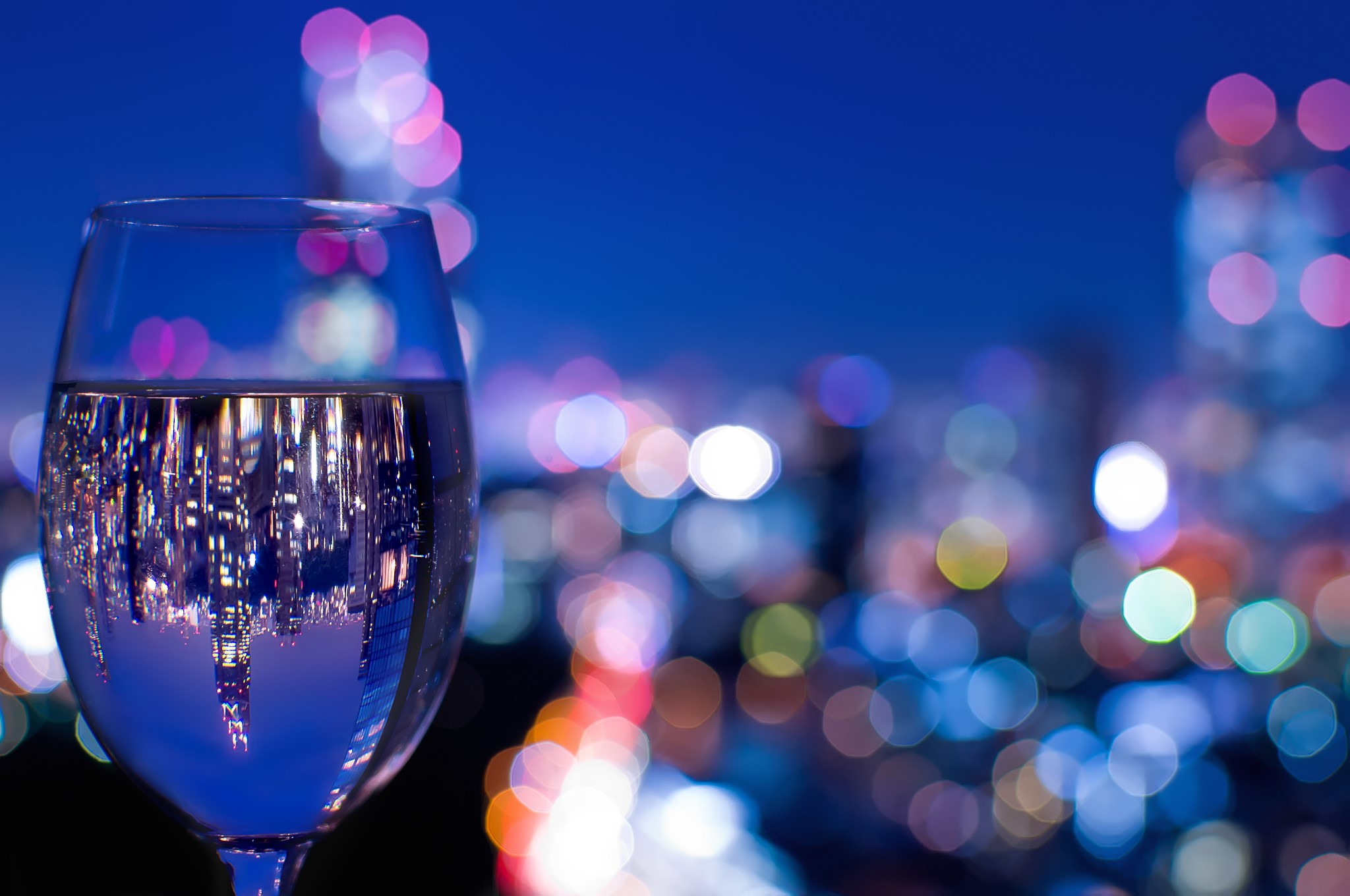 Glass of water reflecting city lights at night HD Wallpaper