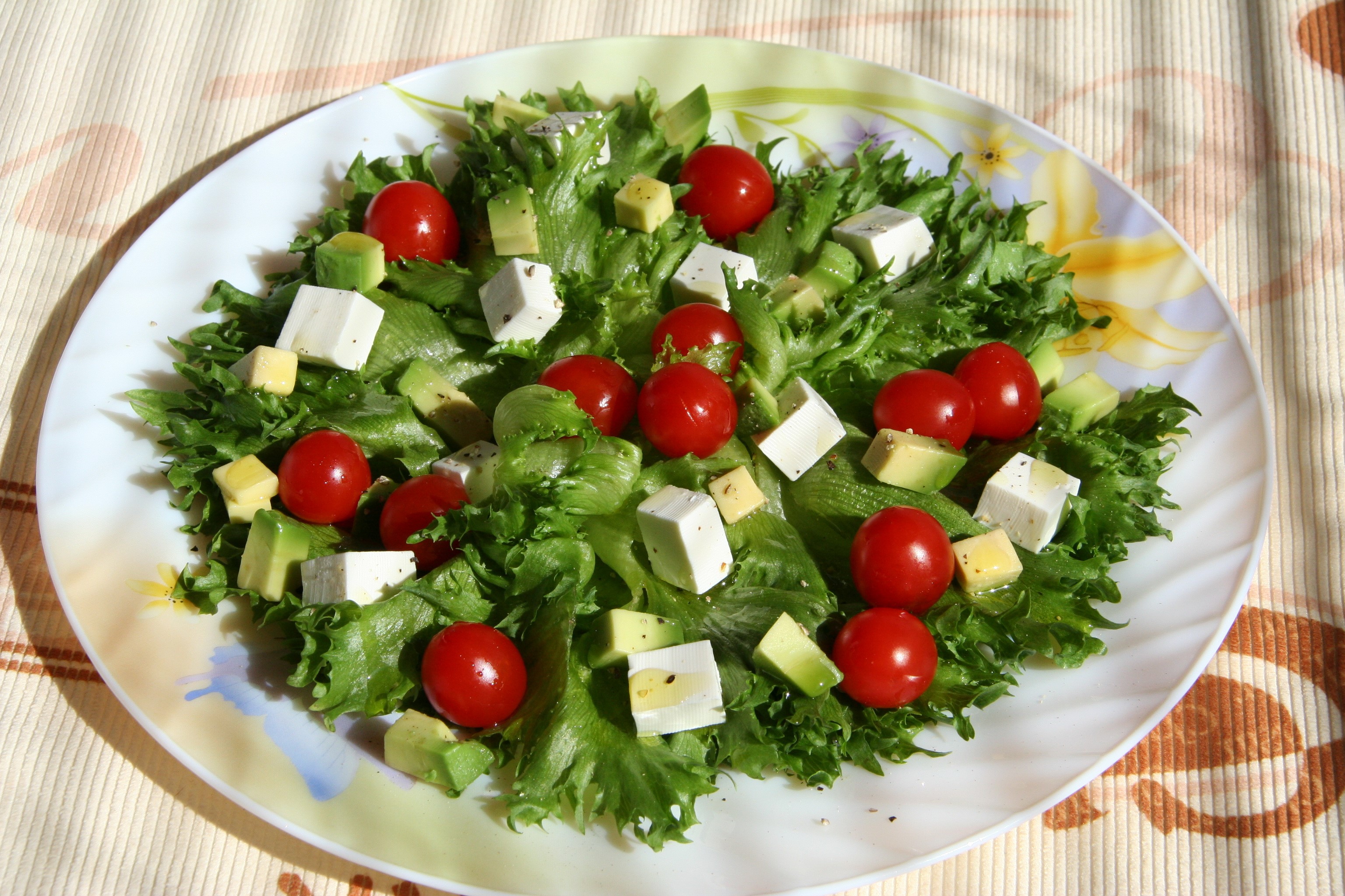 Salad with cherry tomatoes, feta cheese, and avocado on a plate HD Wallpaper