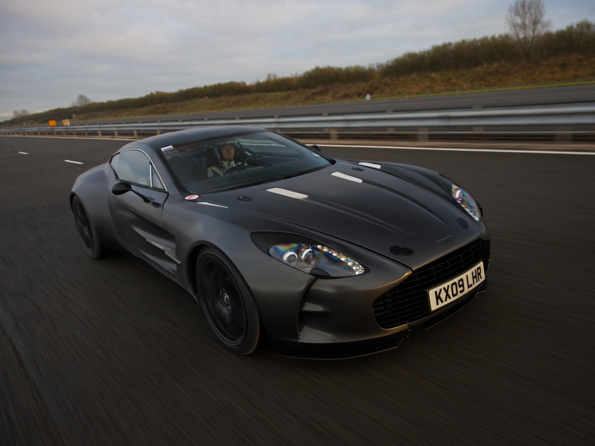 Aston Martin One-77 driving on a highway HD Wallpaper