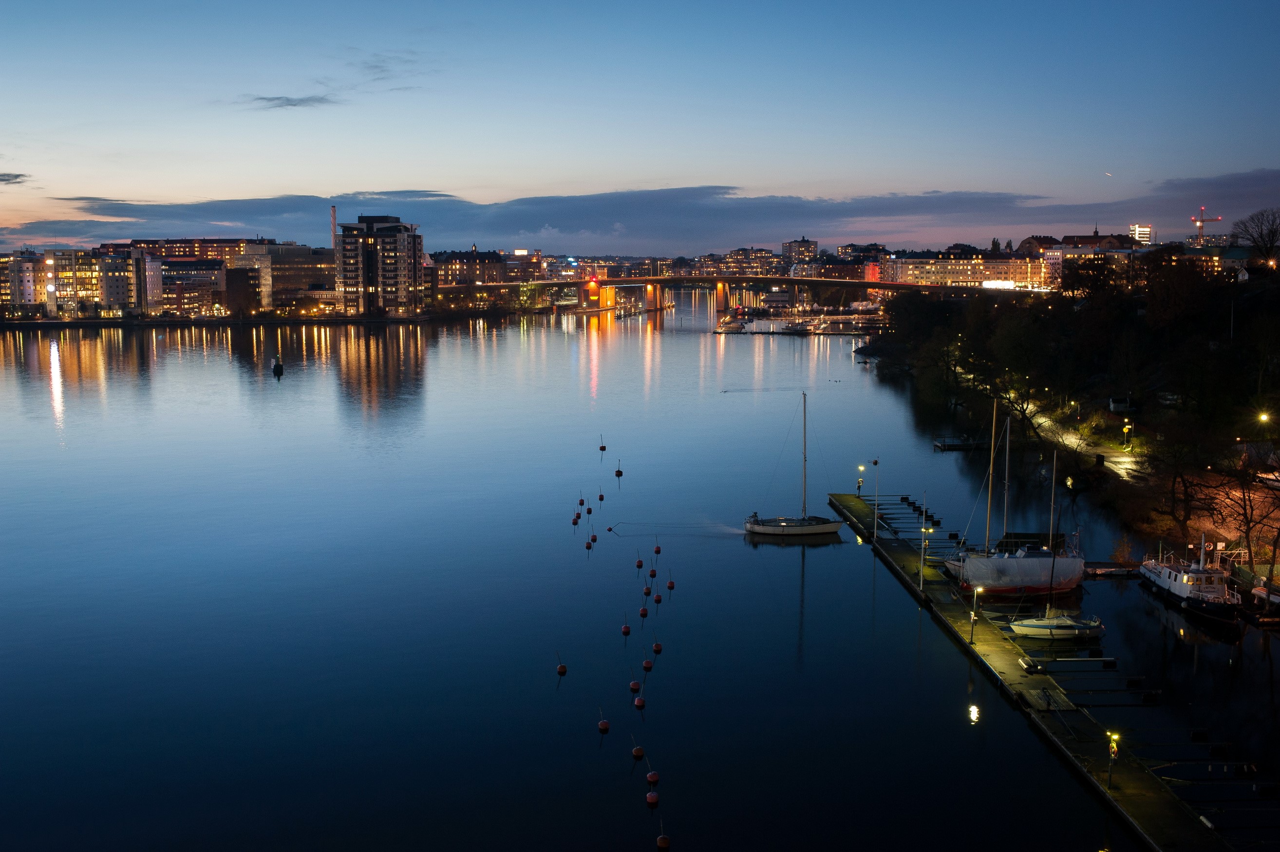 Stockholm waterfront at dusk with city lights and boats HD Wallpaper