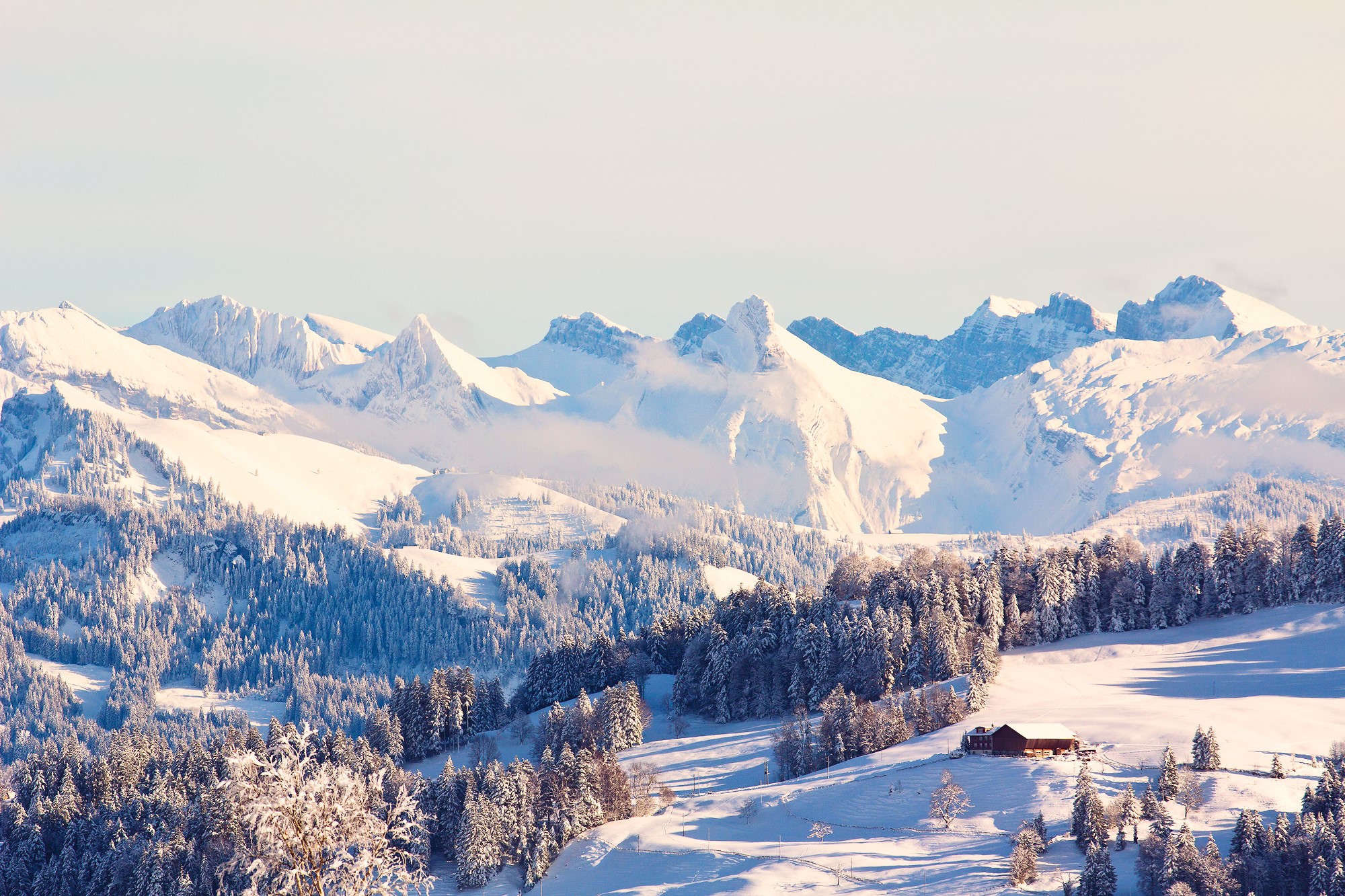 Snowy mountains with a cabin and pine trees HD Wallpaper