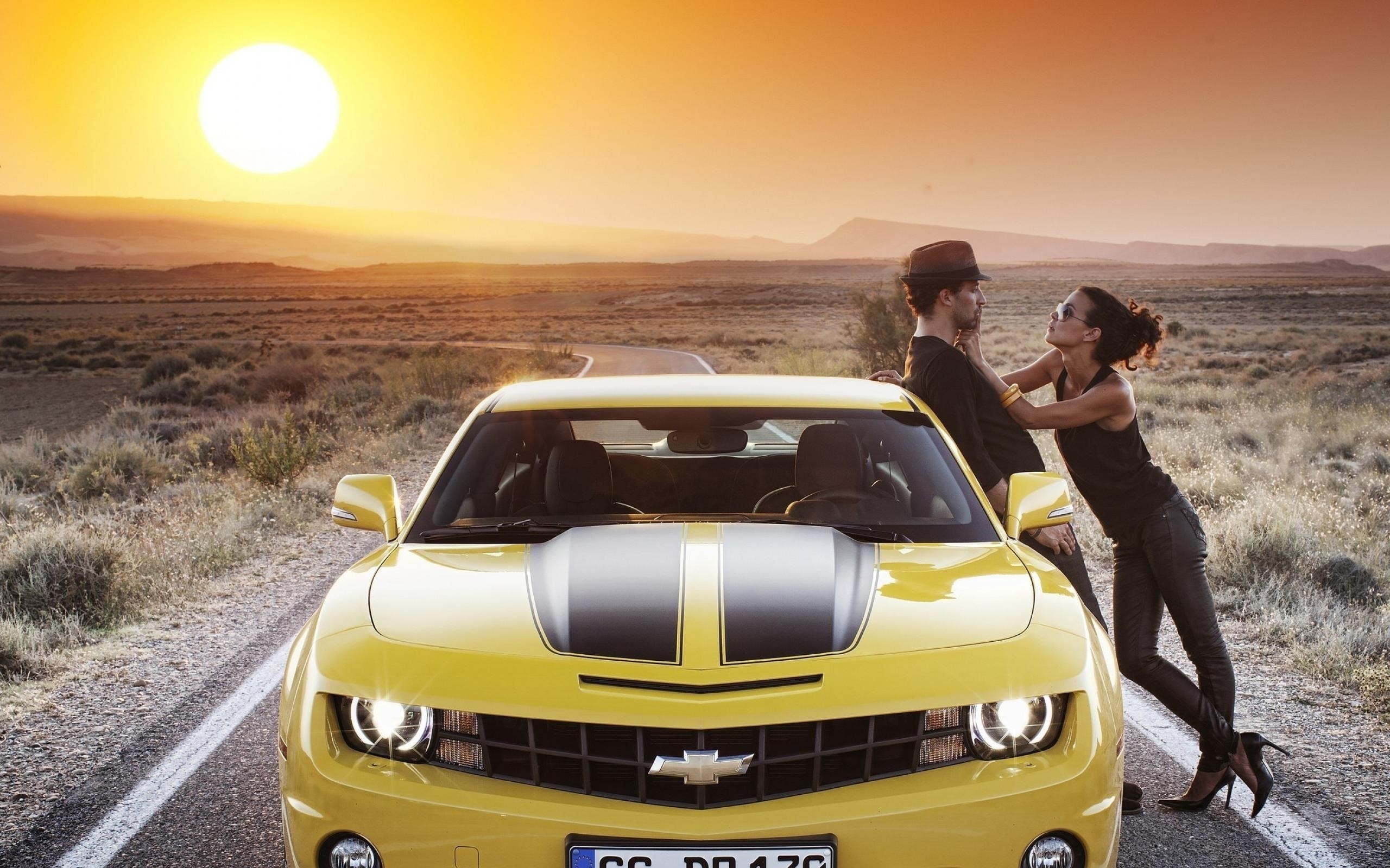 Yellow Chevrolet Camaro with a couple at sunset HD Wallpaper