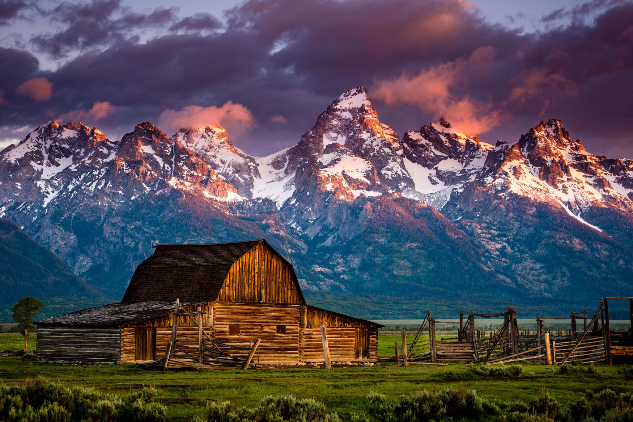 Wooden barn in front of snow-capped mountains at sunset HD Wallpaper