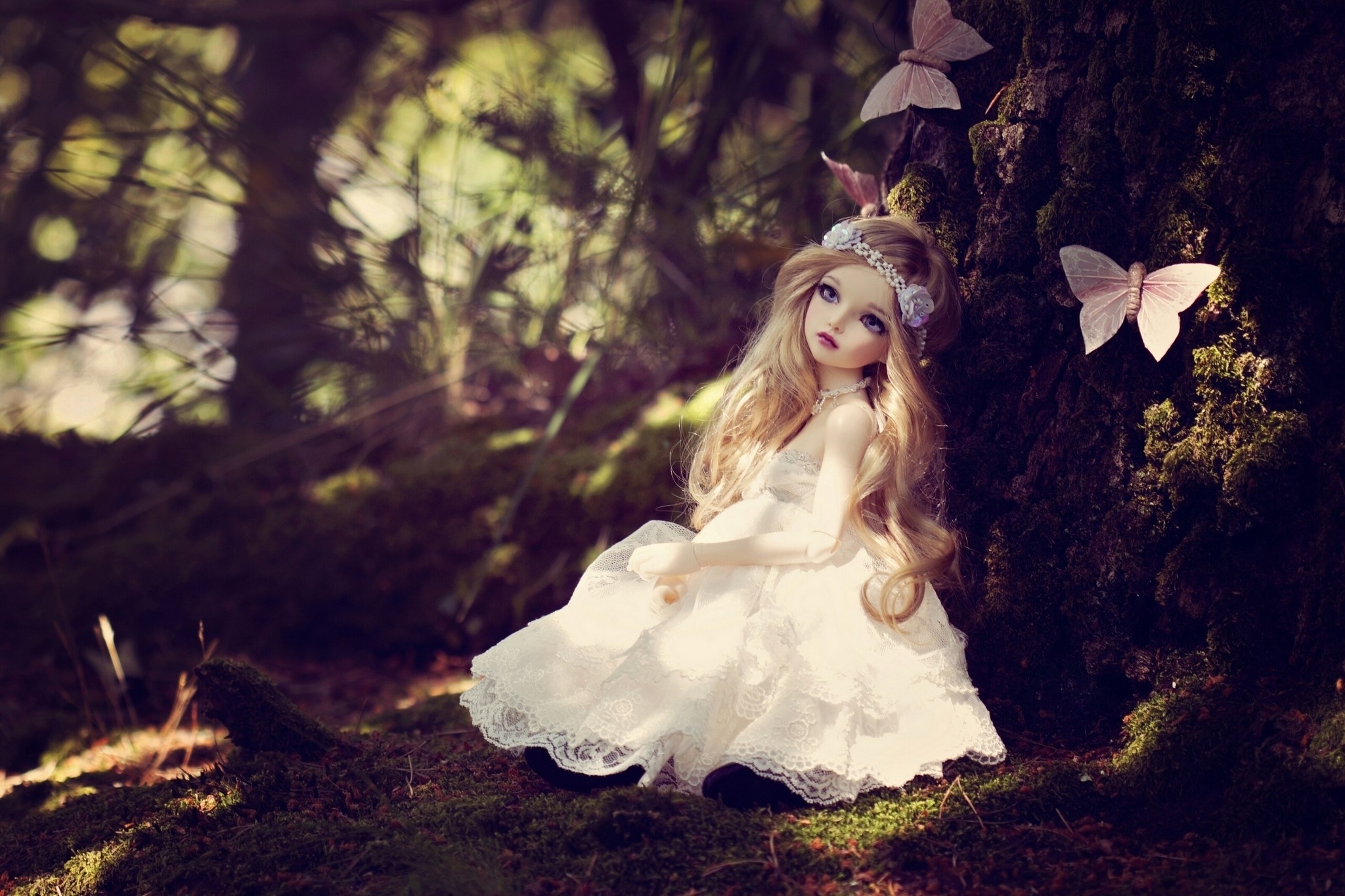 Doll in a white dress sitting in a mossy forest HD Wallpaper