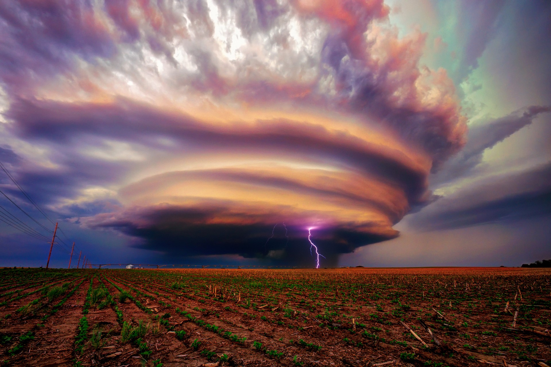 Lightning strikes a massive thundercloud over a farm field in the USA HD Wallpaper