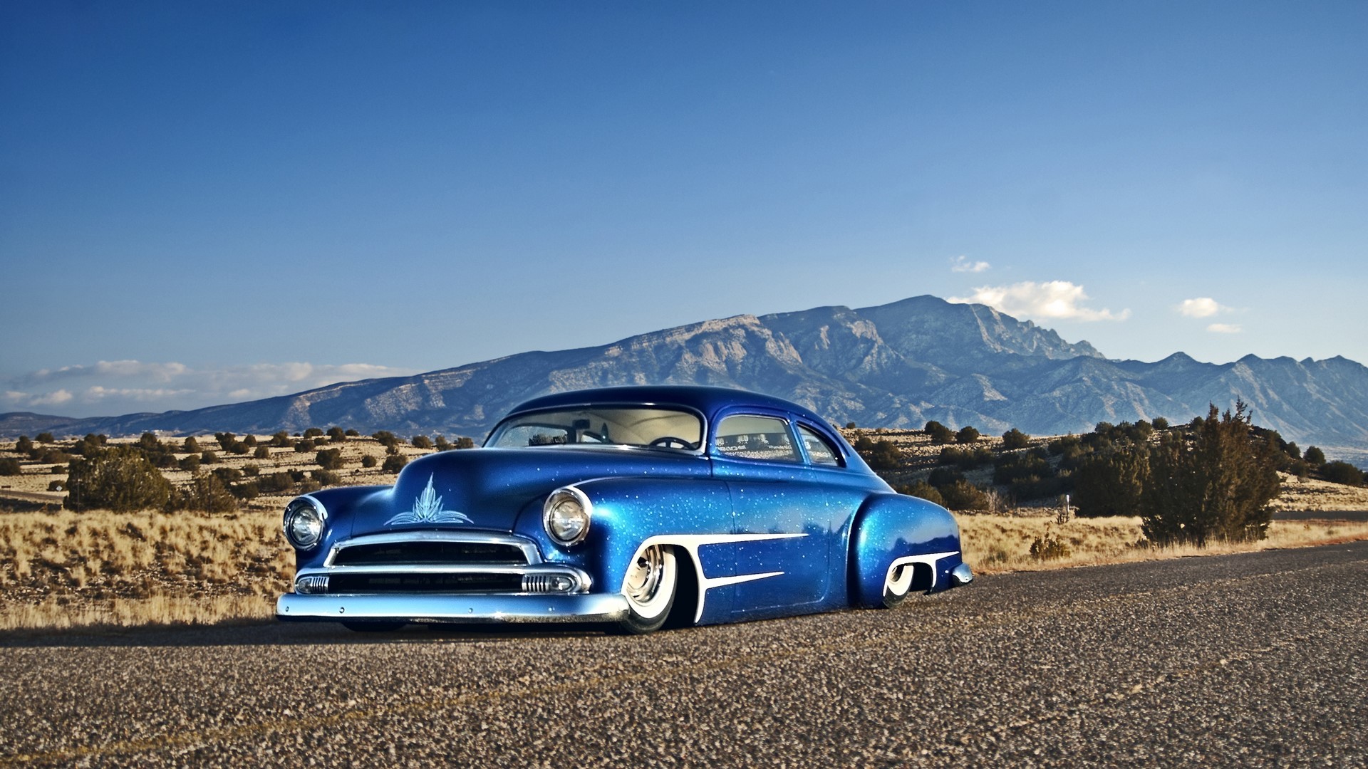 Blue Chevrolet hot rod in a desert landscape with mountains HD Wallpaper