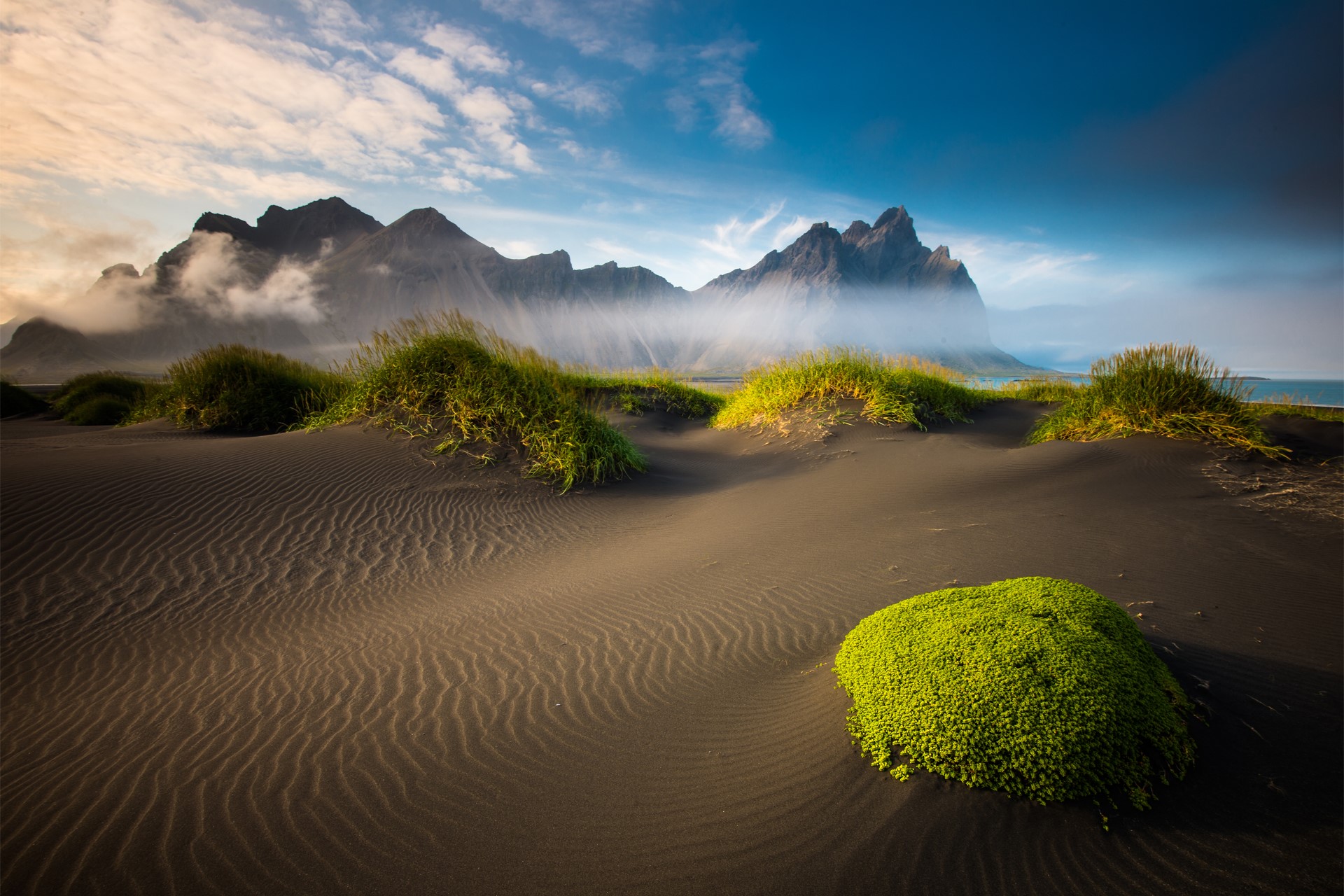 Black sand beach with grass dunes and mountains in Iceland HD Wallpaper