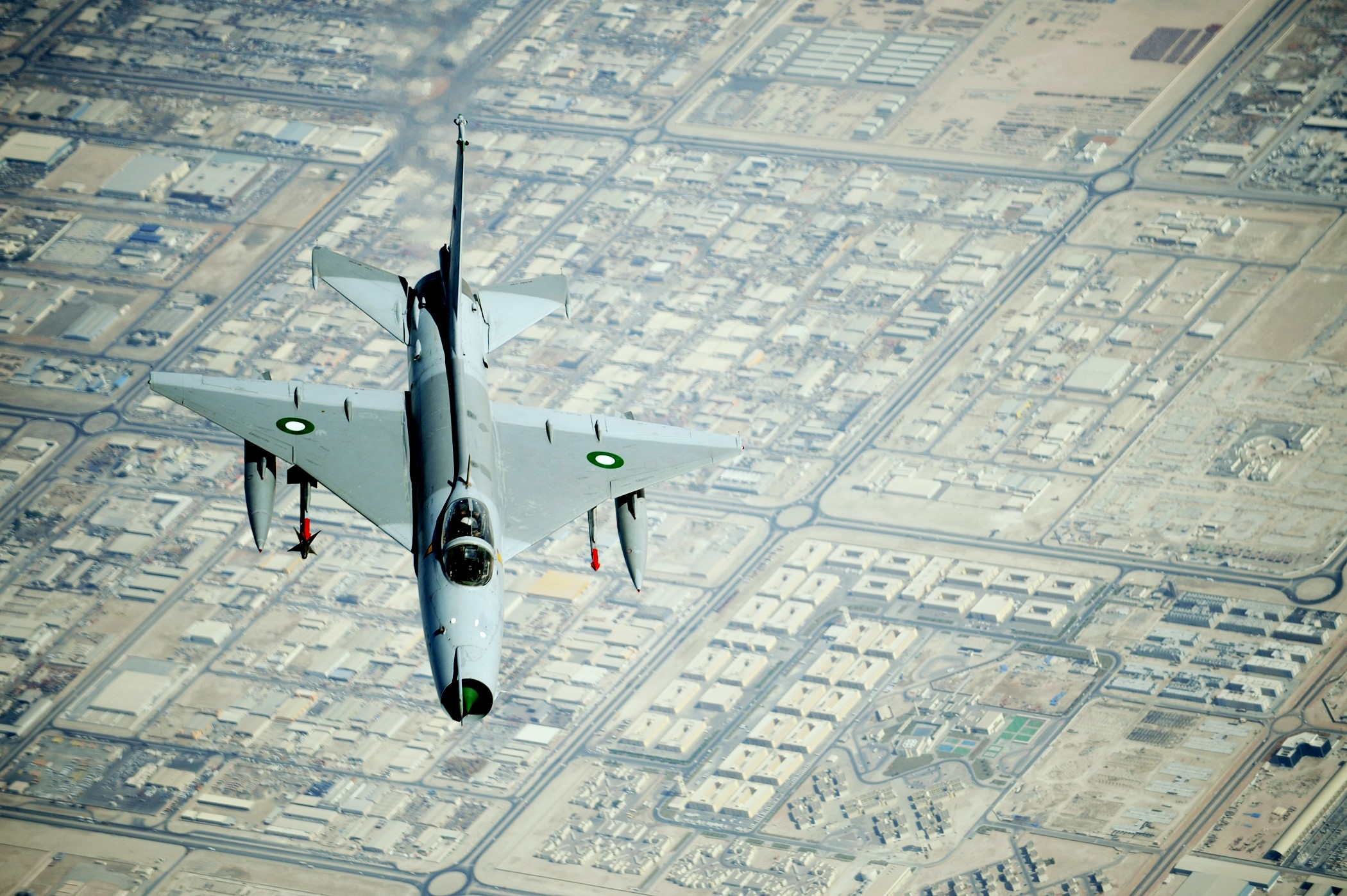 Chengdu J-7 fighter jet flying over a city HD Wallpaper