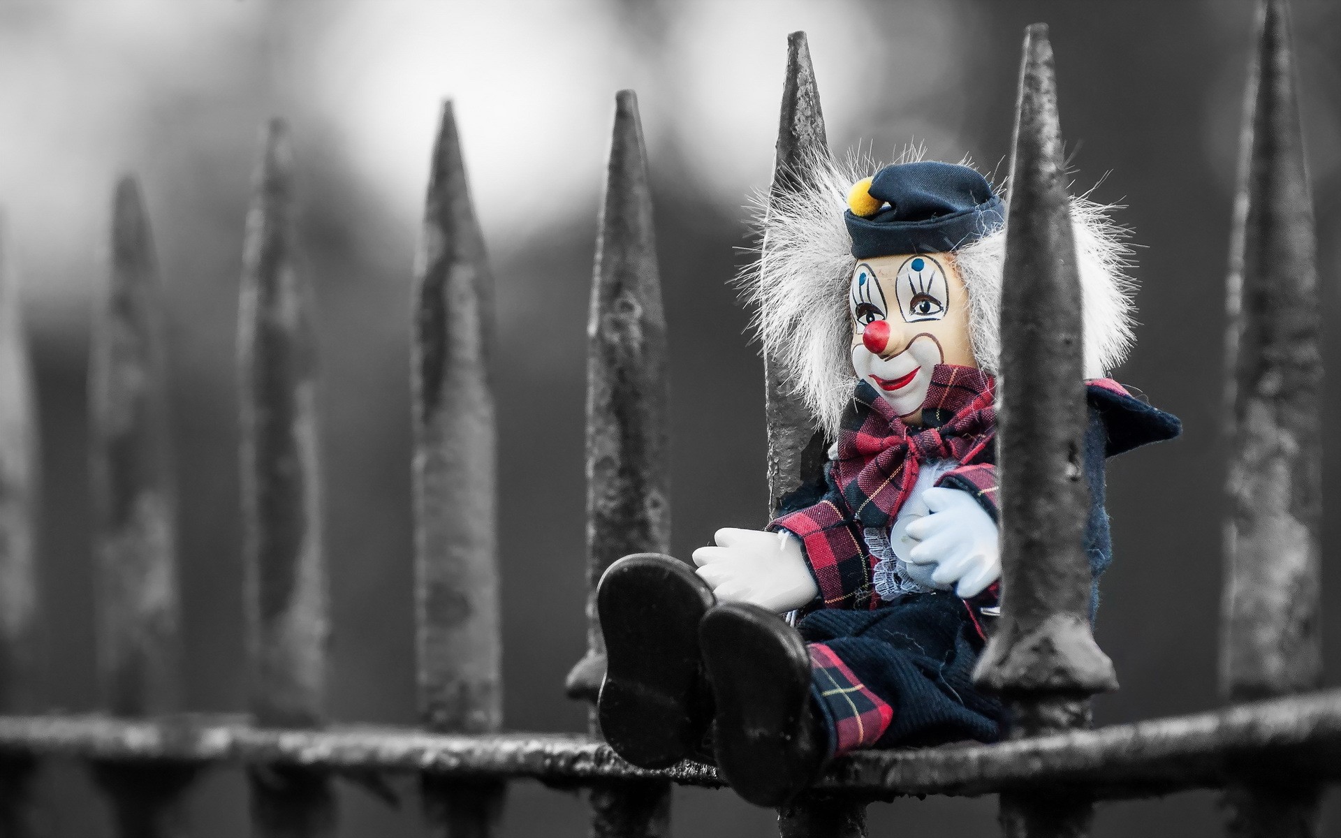 Clown doll sitting on a spiked fence HD Wallpaper