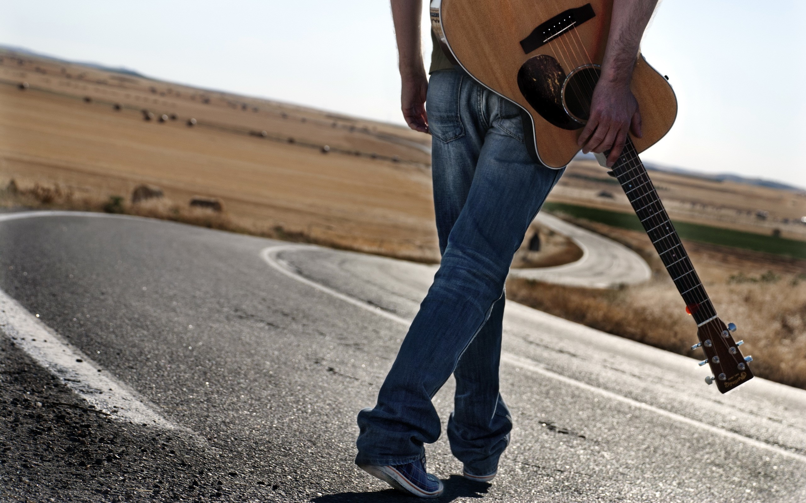 Person with guitar walking on a winding road HD Wallpaper