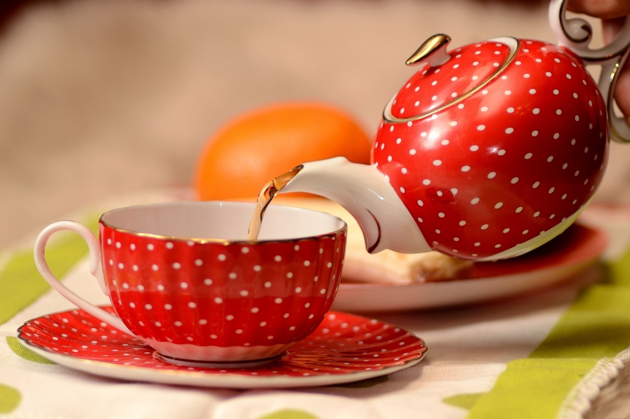 Red polka dot teapot pouring tea into a matching cup and saucer HD Wallpaper
