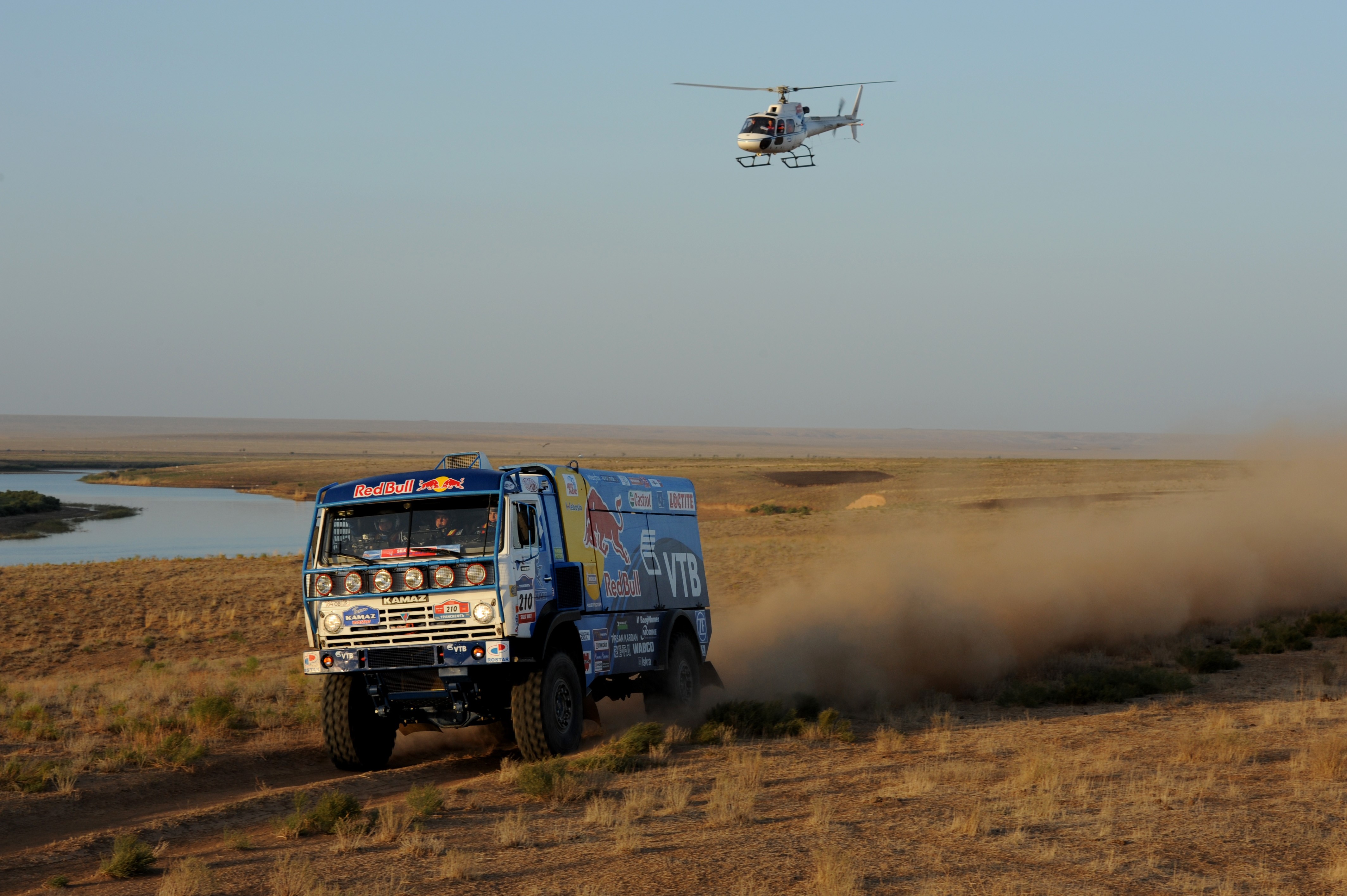 KAMAZ truck and helicopter in a desert landscape HD Wallpaper