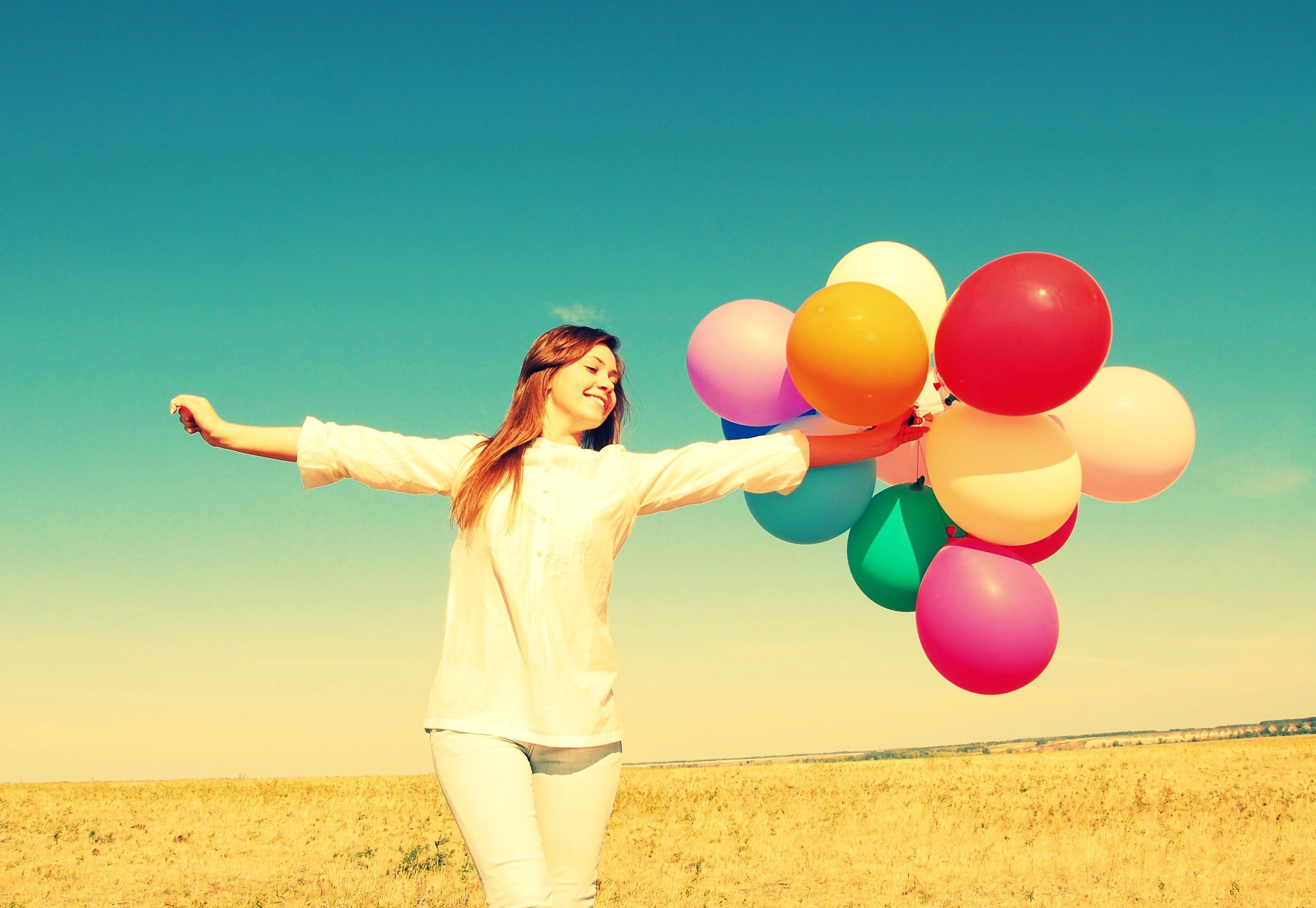 Girl holding colorful balloons in a field HD Wallpaper