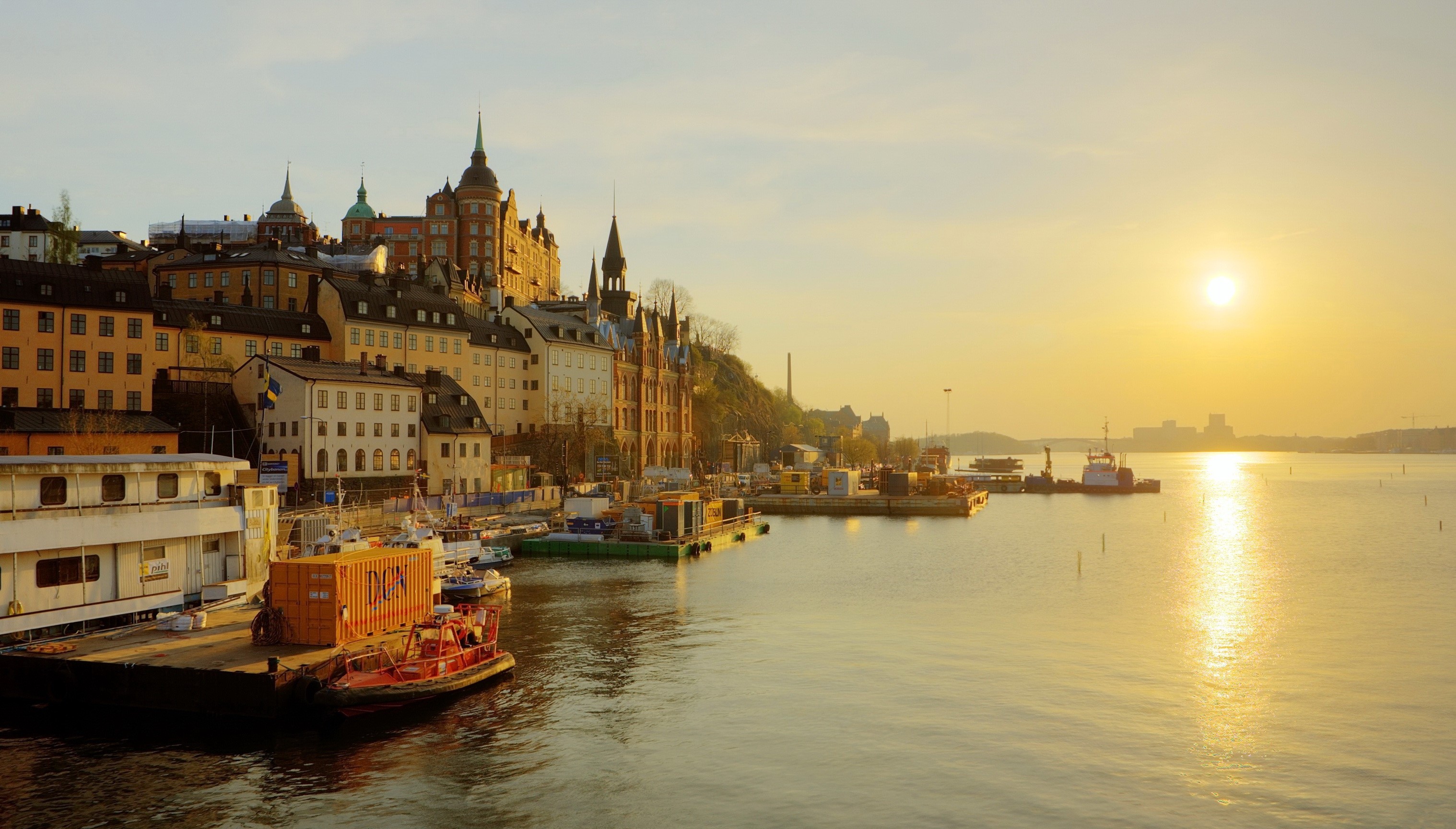 Stockholm waterfront at sunset with buildings and boats HD Wallpaper