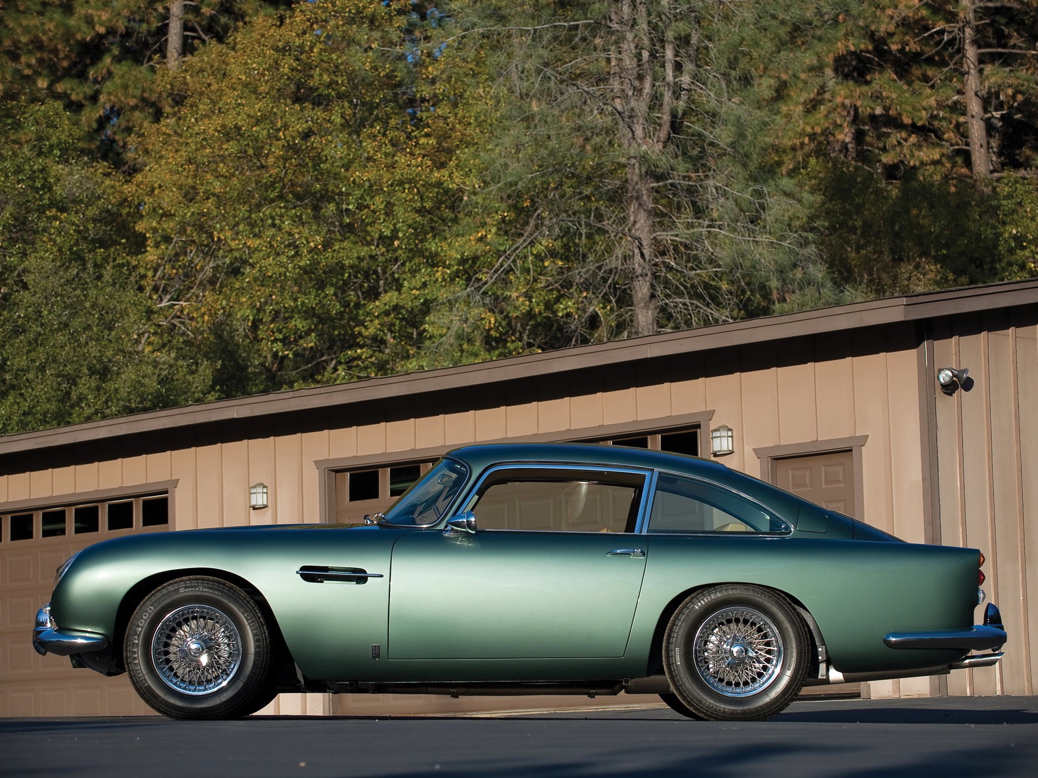 Green 1963 Aston Martin DB5 parked outside a garage HD Wallpaper