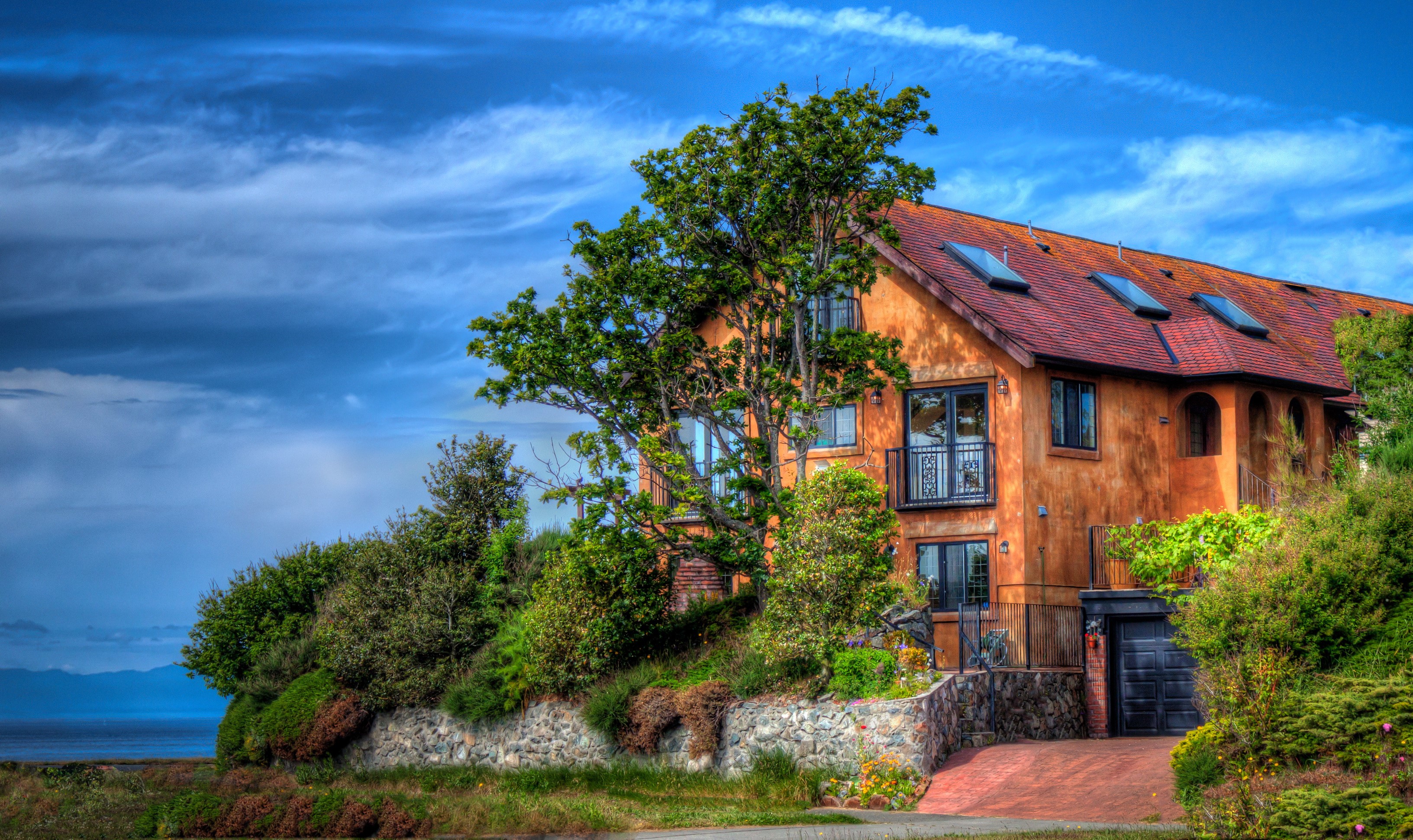 Orange house with red roof and trees by the ocean HD Wallpaper