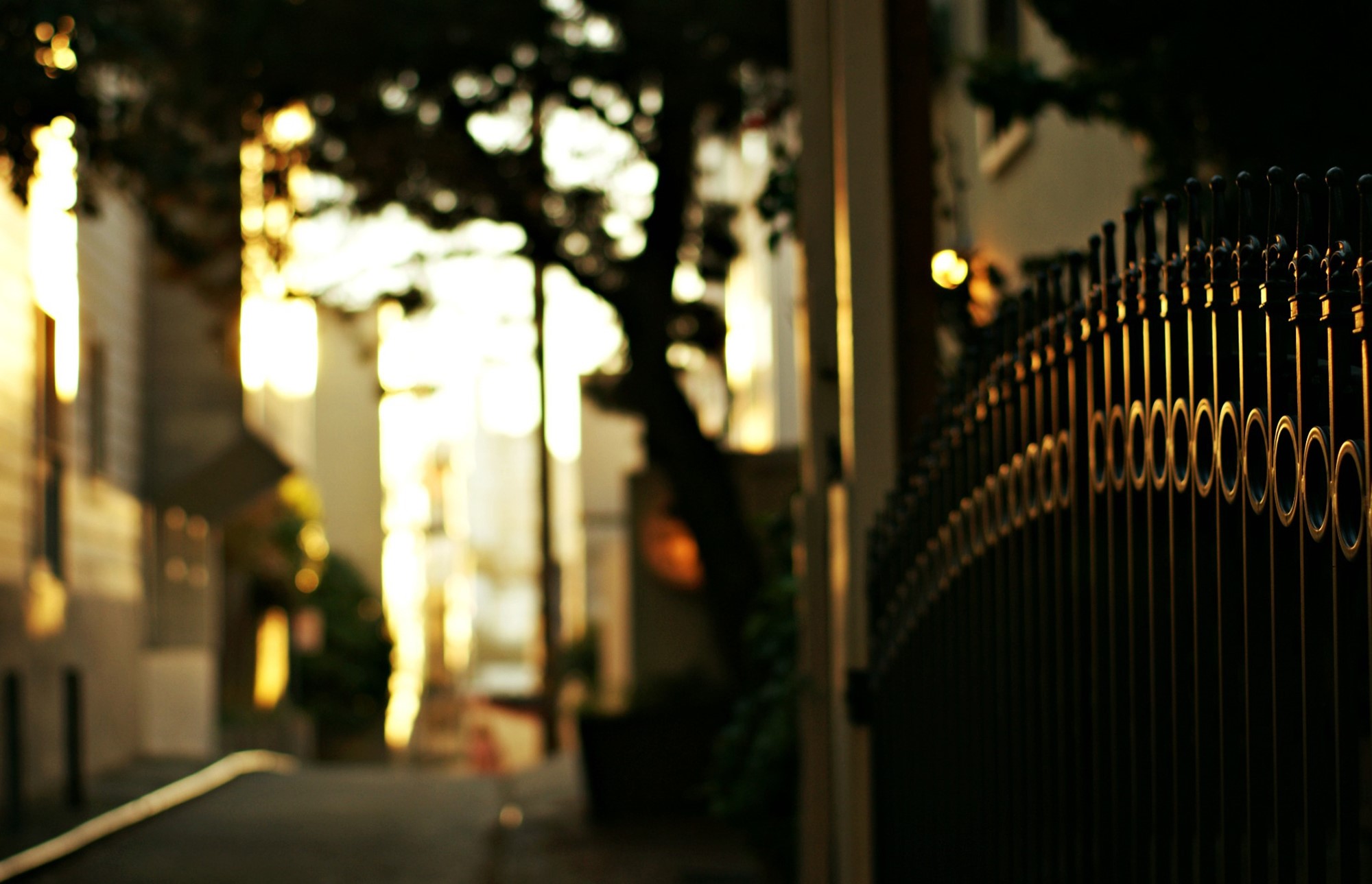 Street with a fence and buildings at sunset HD Wallpaper