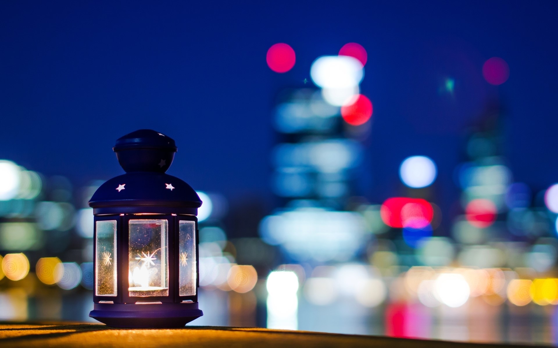 Lantern with a candle at night with city lights HD Wallpaper