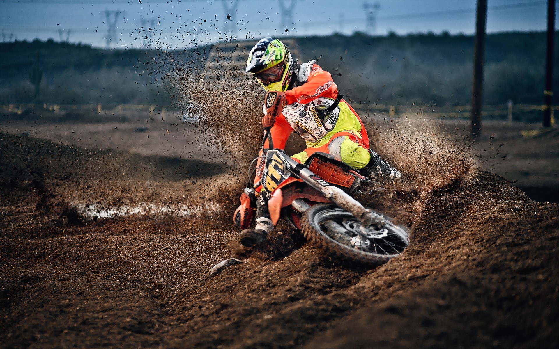 Motocross rider kicking up mud on a dirt track HD Wallpaper