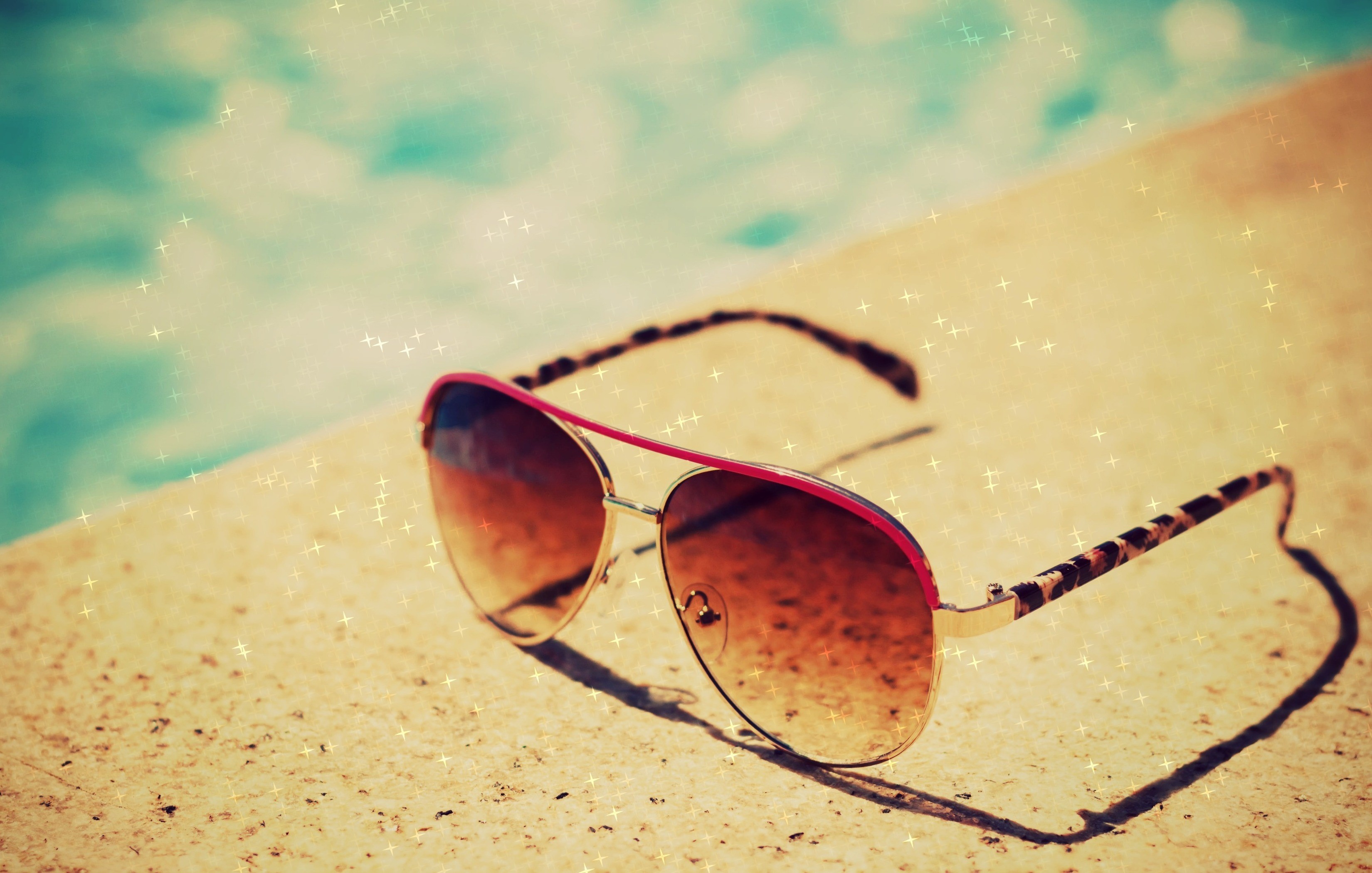 Aviator sunglasses with leopard print arms by a pool HD Wallpaper