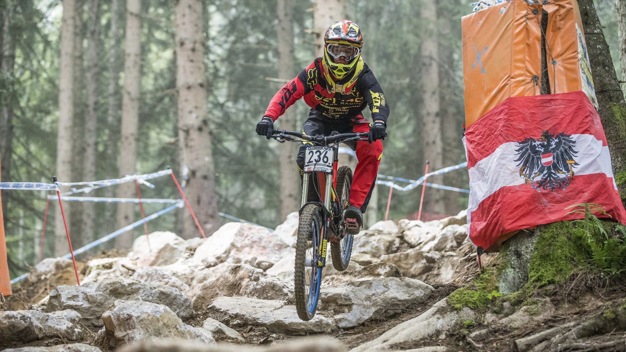 Downhill mountain biker on rocky terrain with Austrian flag HD Wallpaper