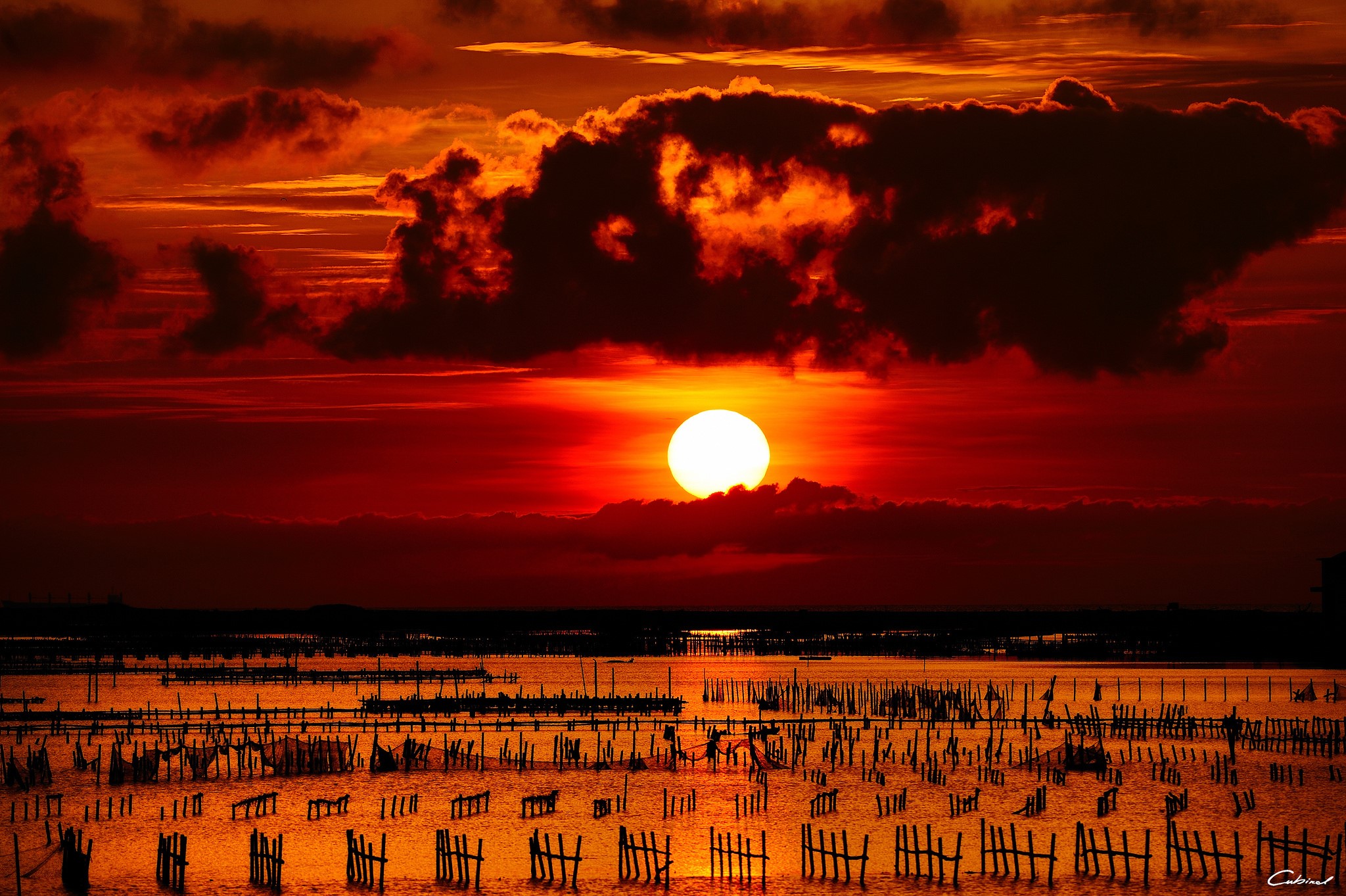Sunset over a body of water with wooden posts HD Wallpaper