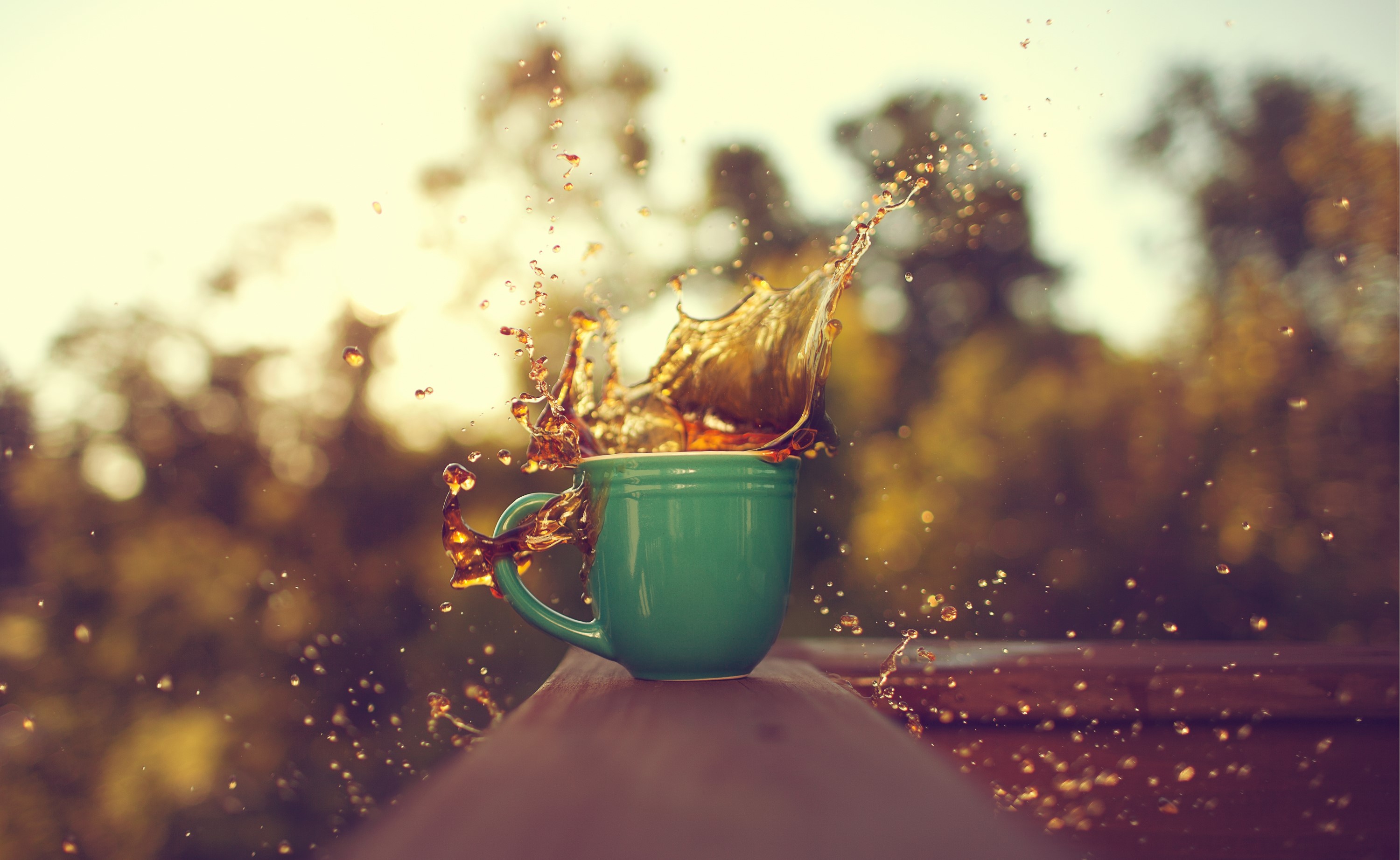 Coffee splashing out of a green mug outdoors HD Wallpaper