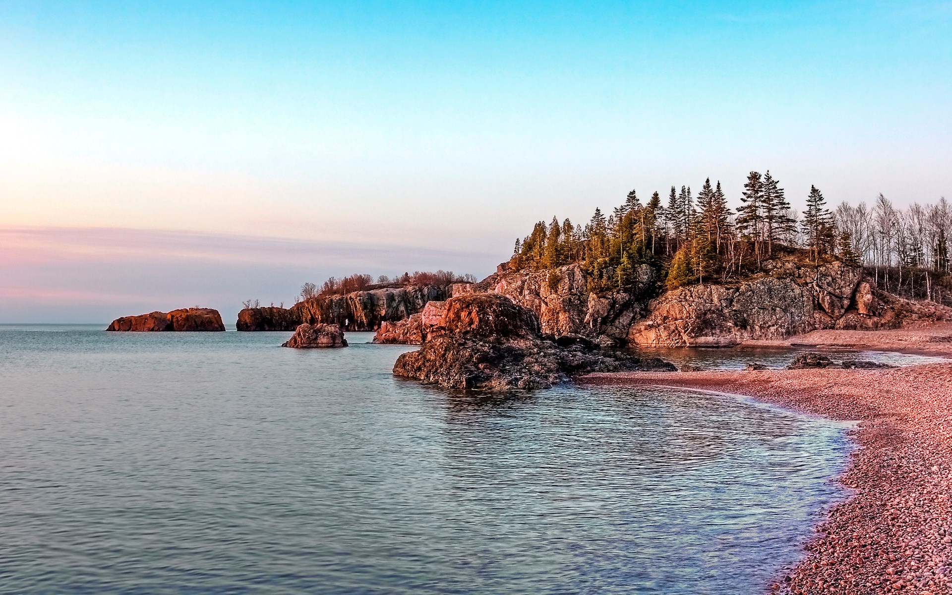 Rocky shoreline with trees at sunset HD Wallpaper