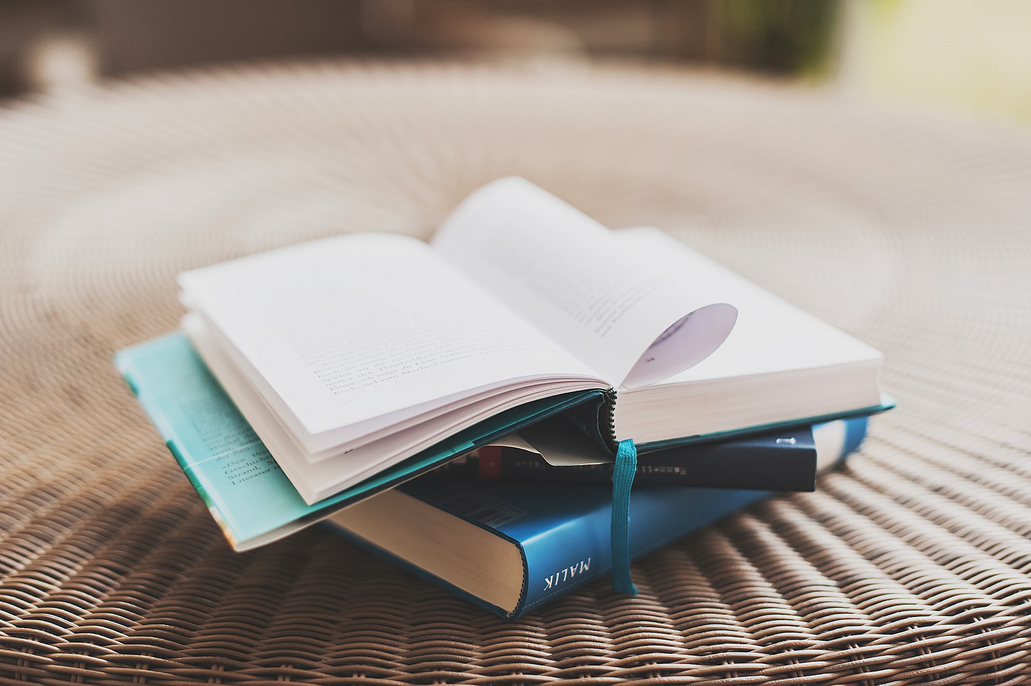 Stack of books on a woven surface HD Wallpaper