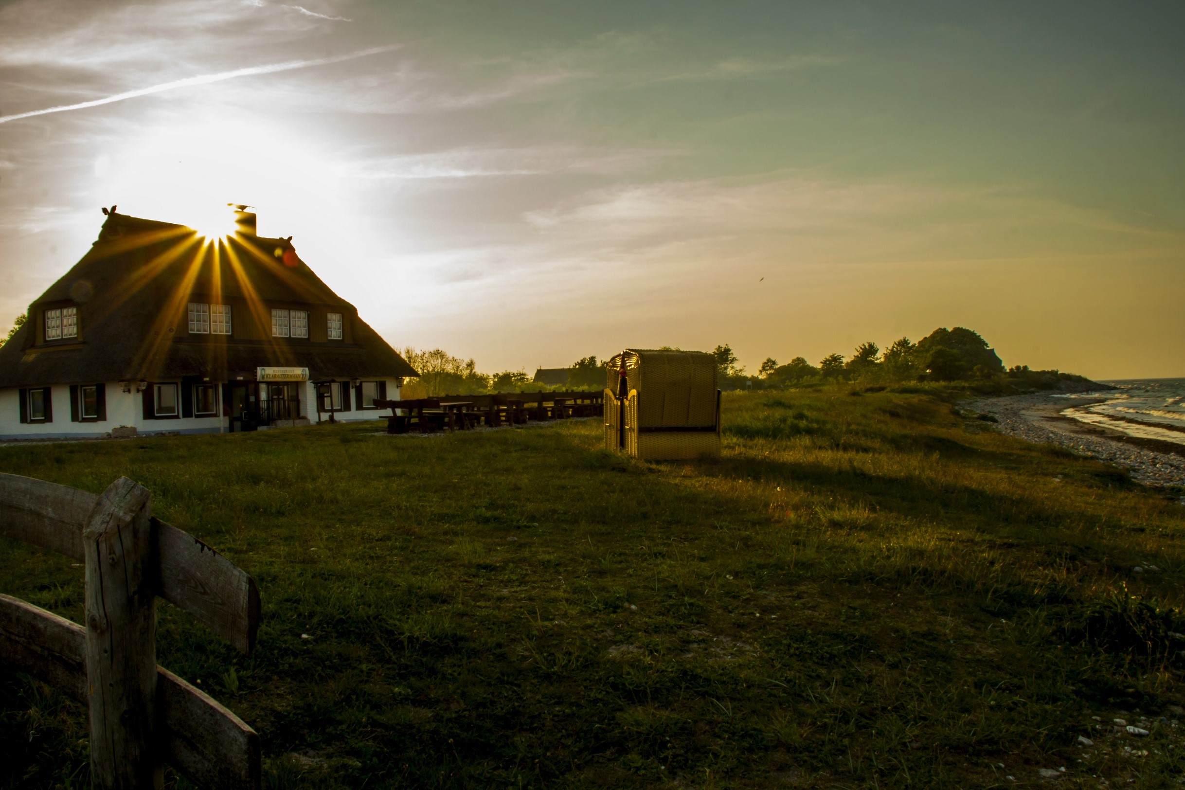 Thatched roof house by the sea at sunset HD Wallpaper